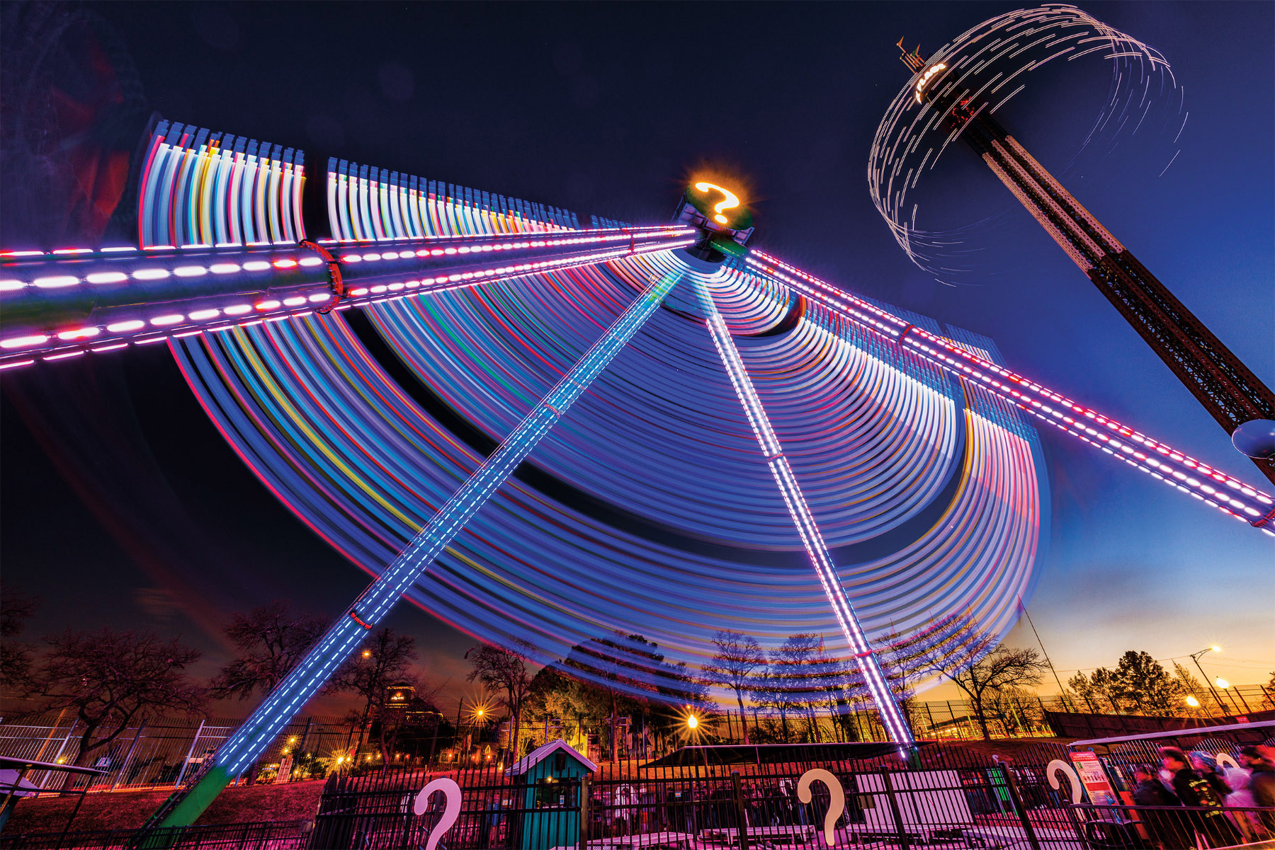 A picture of amusement park rides, their lights obscured and blurred by a long exposure