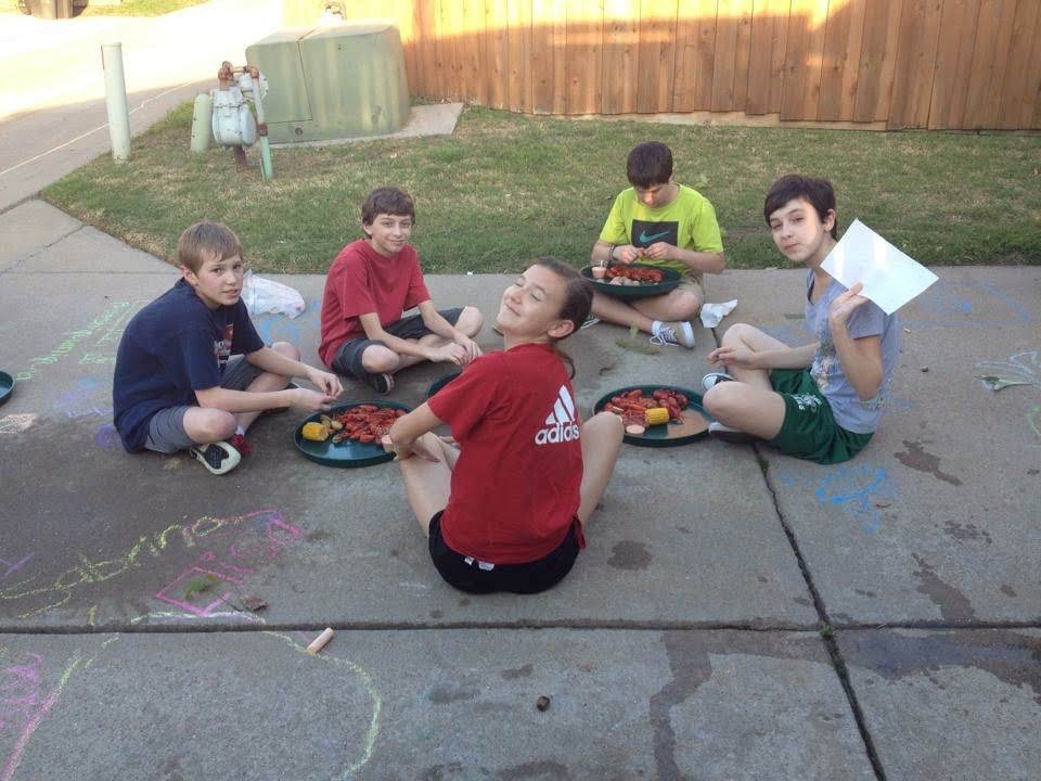 Kids sit in the driveway eating crawfish