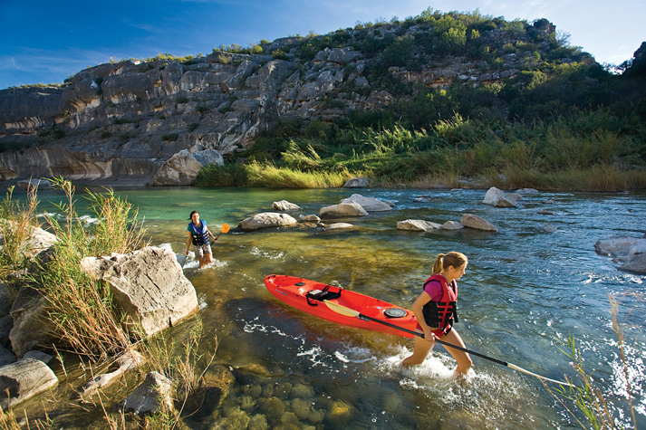 Amie Hufton, right, and Keri Thomas pull their kayaks upstream in the Pecos River at the head of the lake. (Photo by Laurence Parent)
