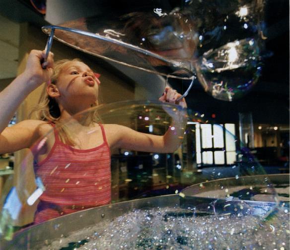 Girl blows bubbles at the Bounce exhibit