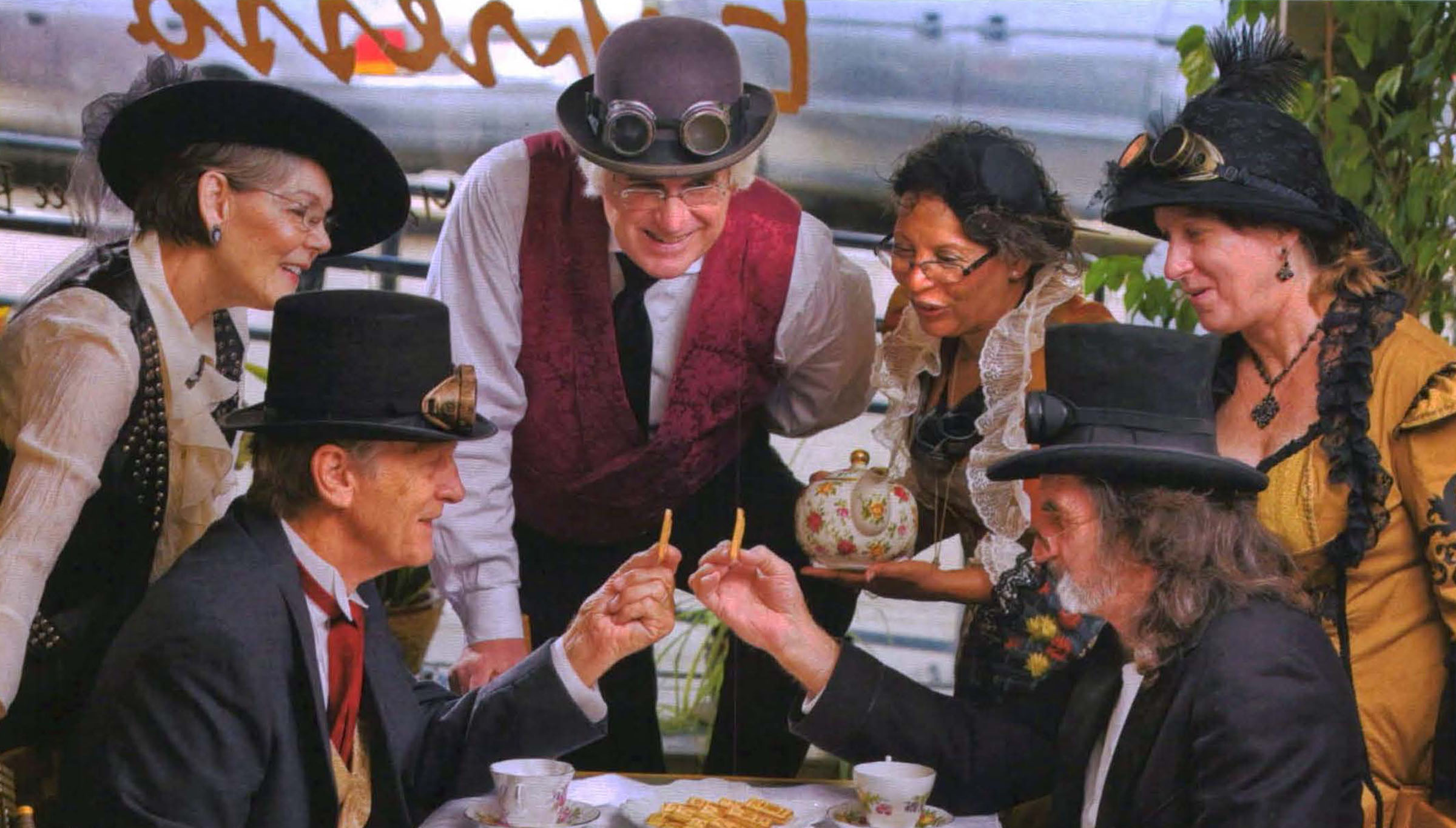 Six people in costume surround a table