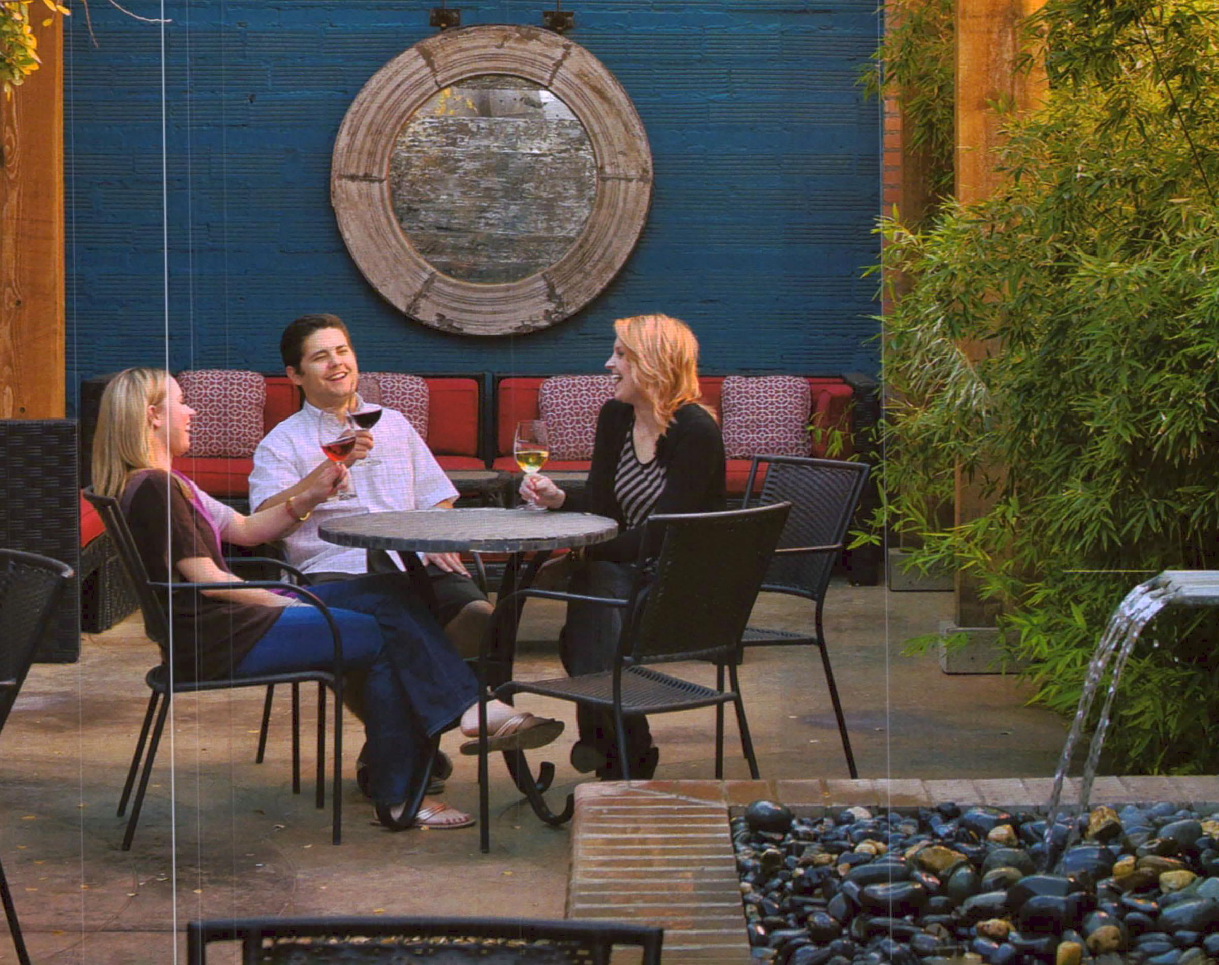 Three people drink wine outside of a winery
