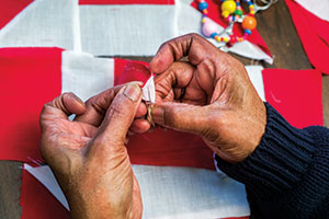 Vernelle Richardson hand-stitches a monkey wrench block for one of the Pleasant Hill Quilting Group’s blankets.