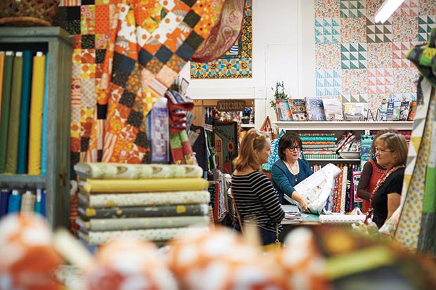 Francine Pons, co-owner of Las Colchas, rolls out some fabric in her store.
