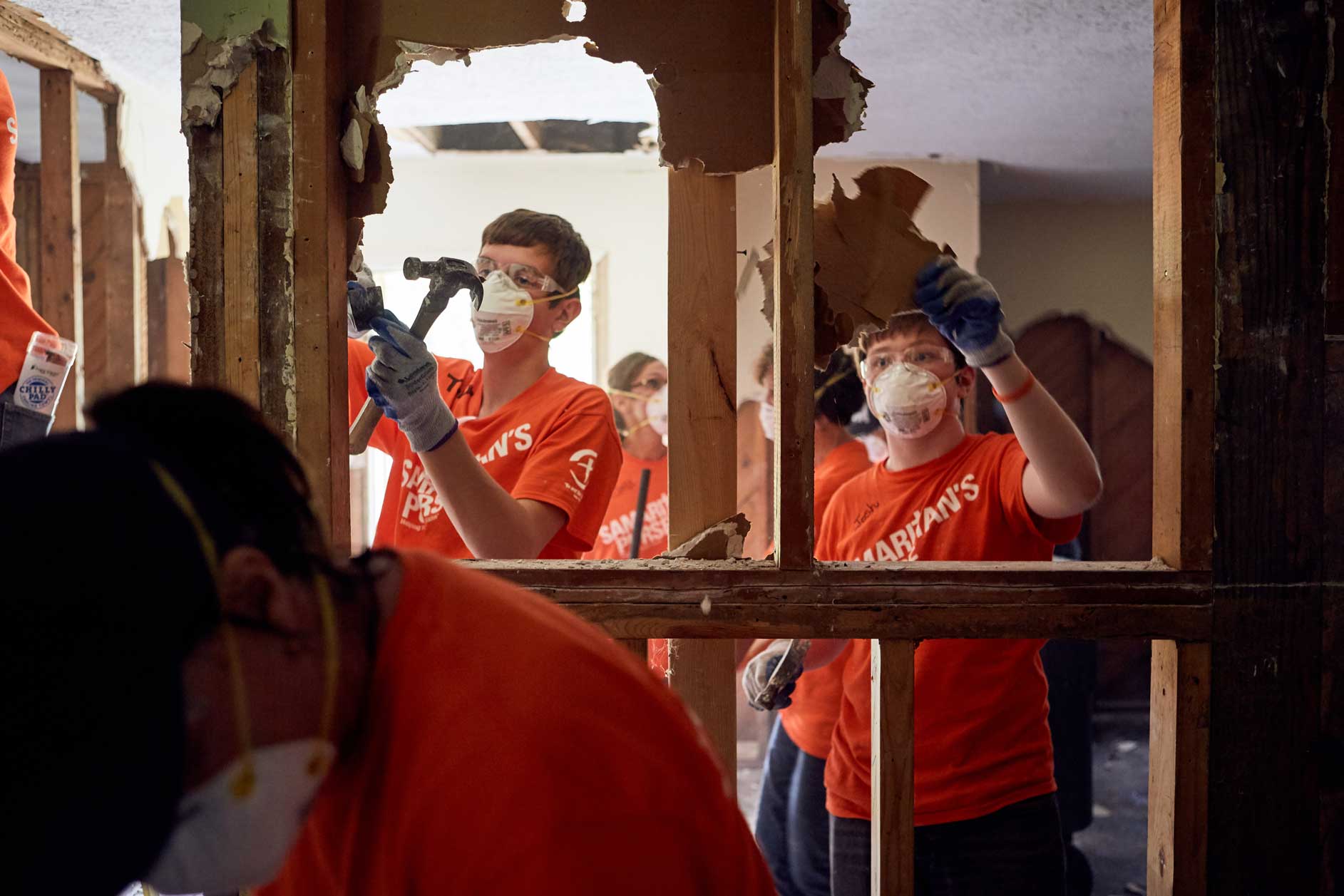 Volunteers removing drywall from a flooded house.