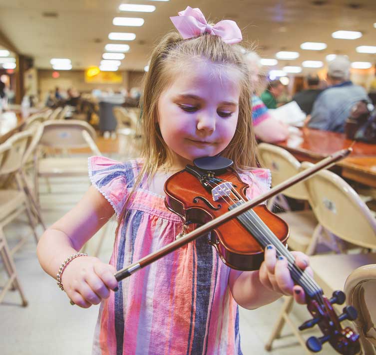 A young girls shows off her fiddle skills.
