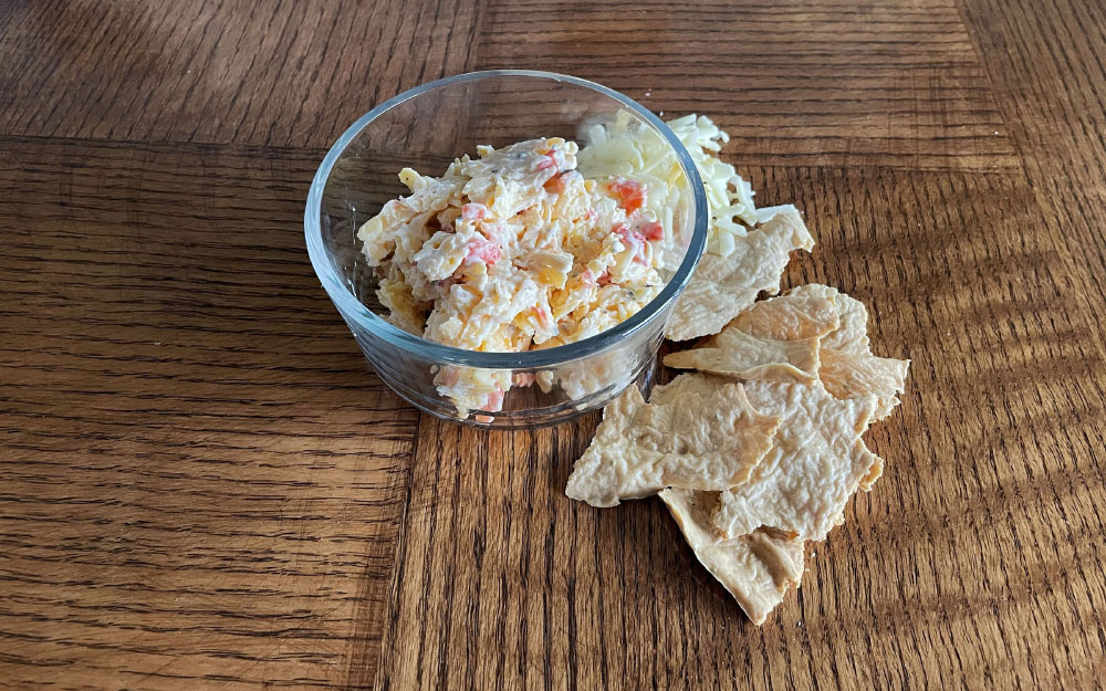 A glass dish of pimento cheese with crackers