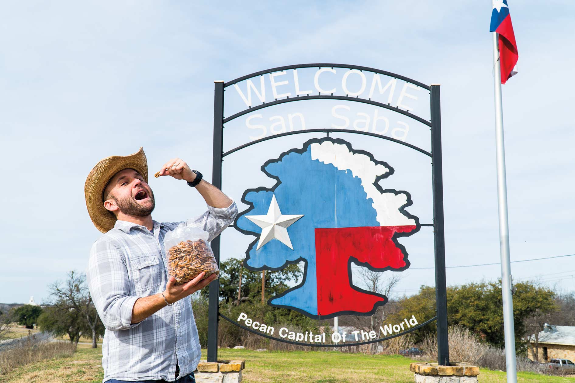 Chet Garner eats pecans by the Pecan Capital of Texas sign