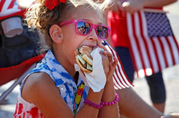 Young girl eating at 4th of July parade