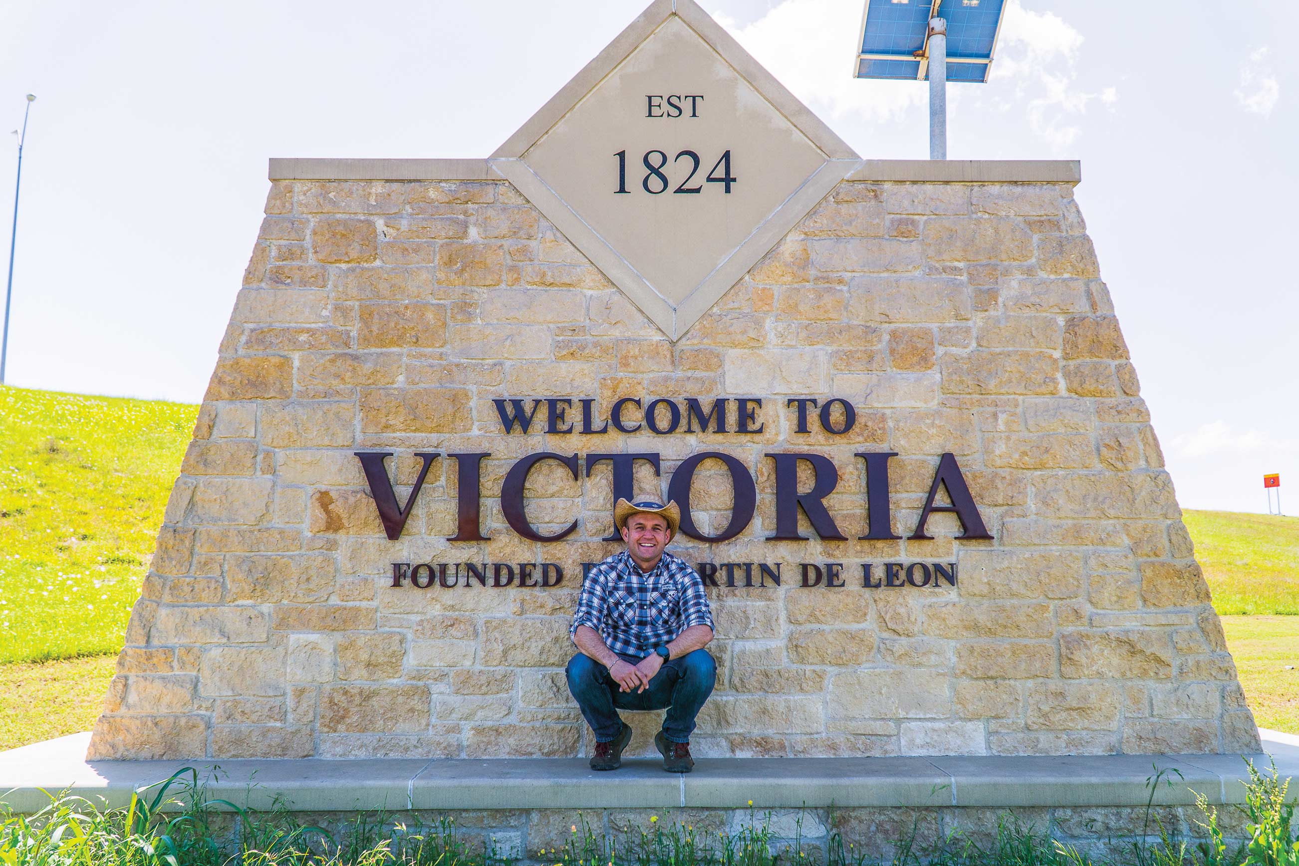 Chet Garner in front of the Welcome to Victoria sign