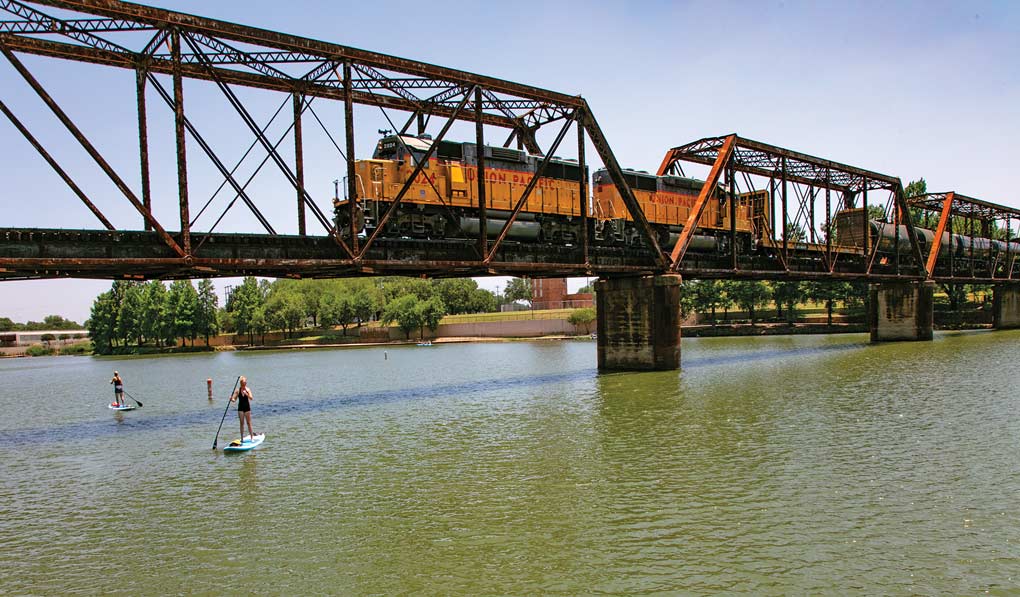 Railroad with train crossing and paddleboarders in the Brazos River below