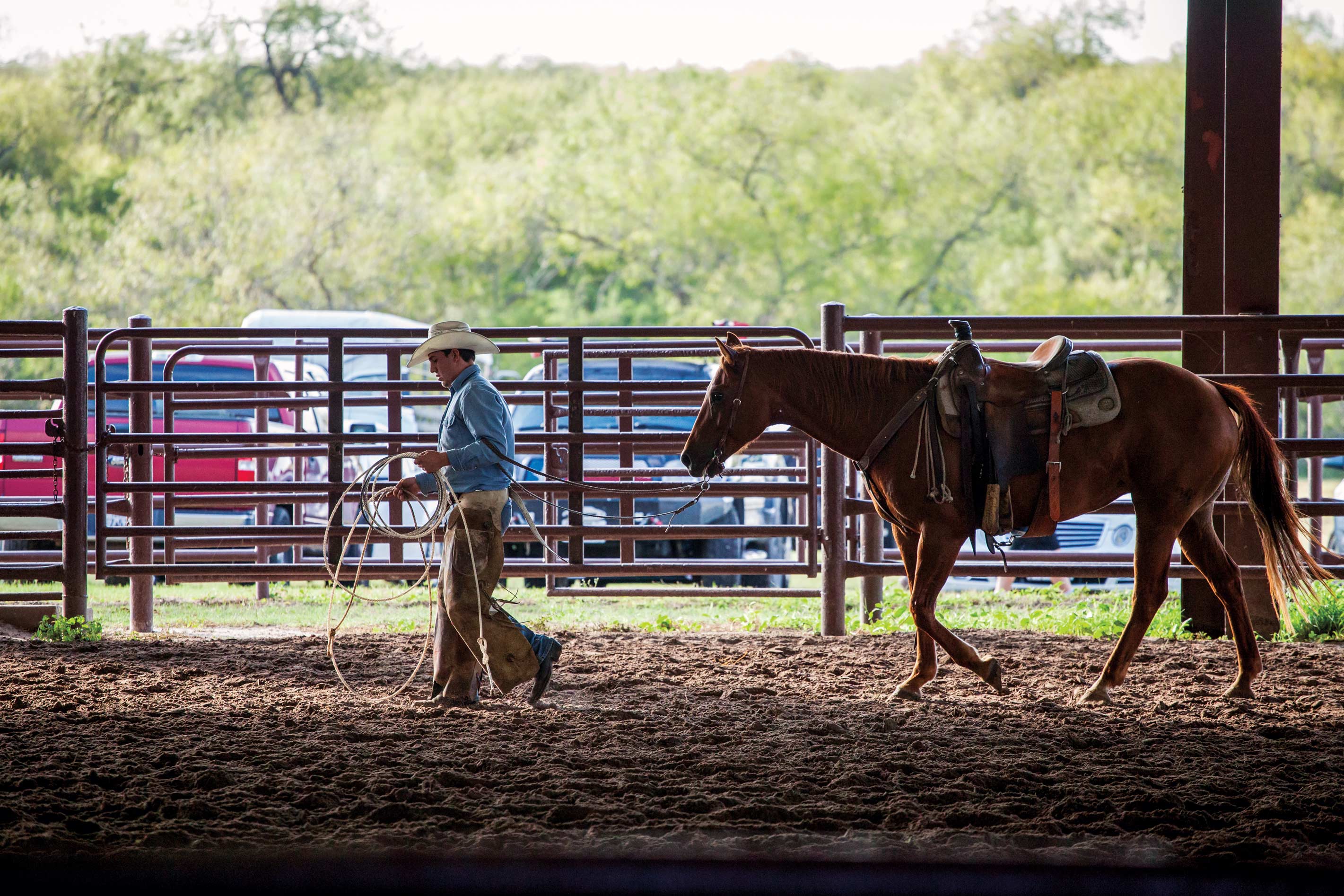 A cowboy leads a horse through a barn