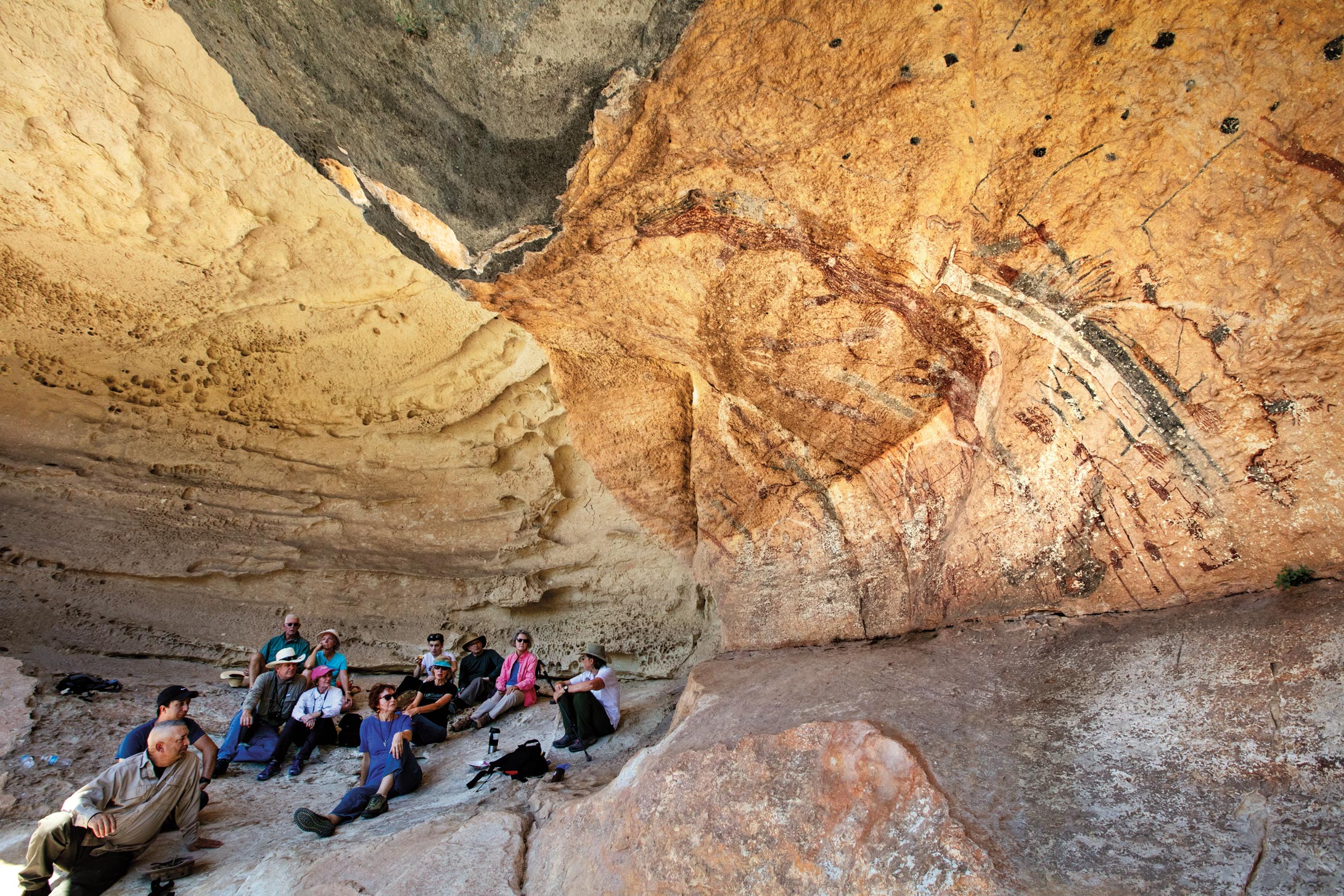 Visitors sit in a rock shelter