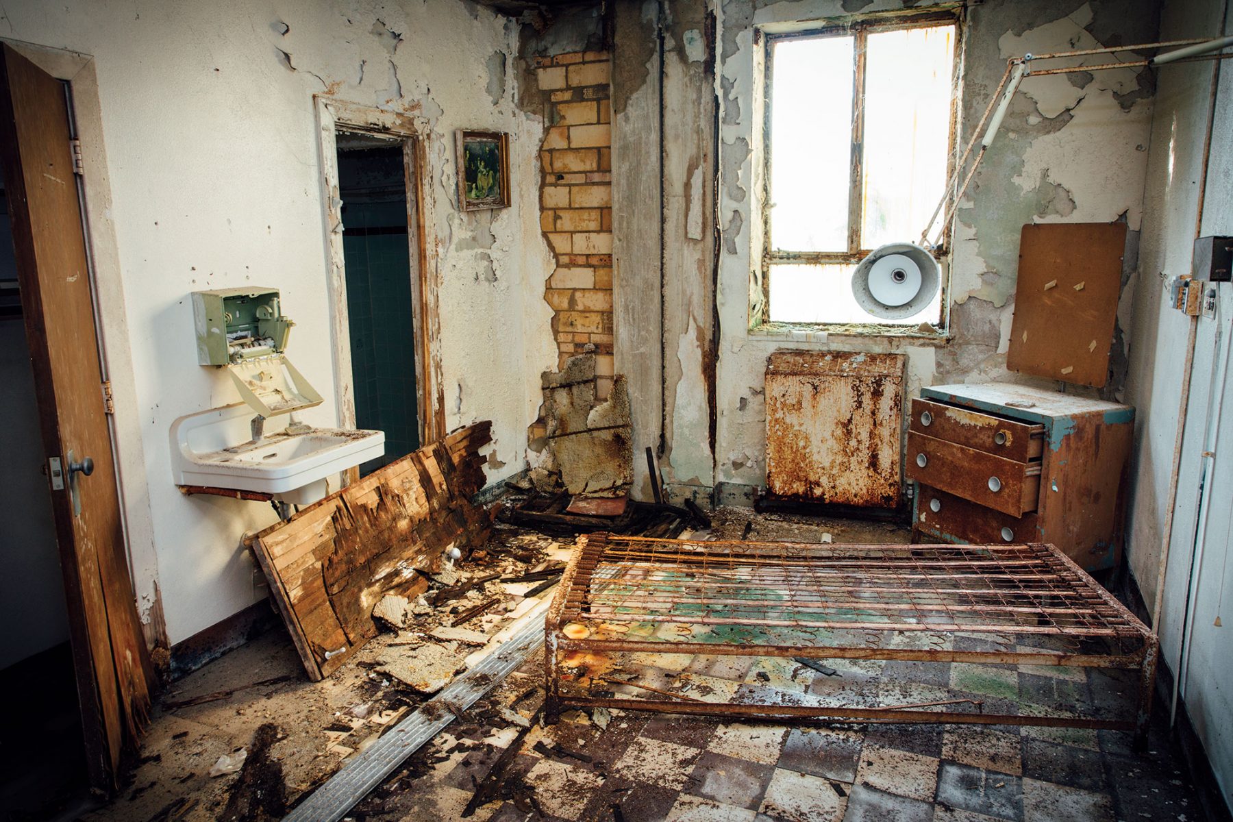 The interior of a dilapidated room with exposed brick and worn furniture showing