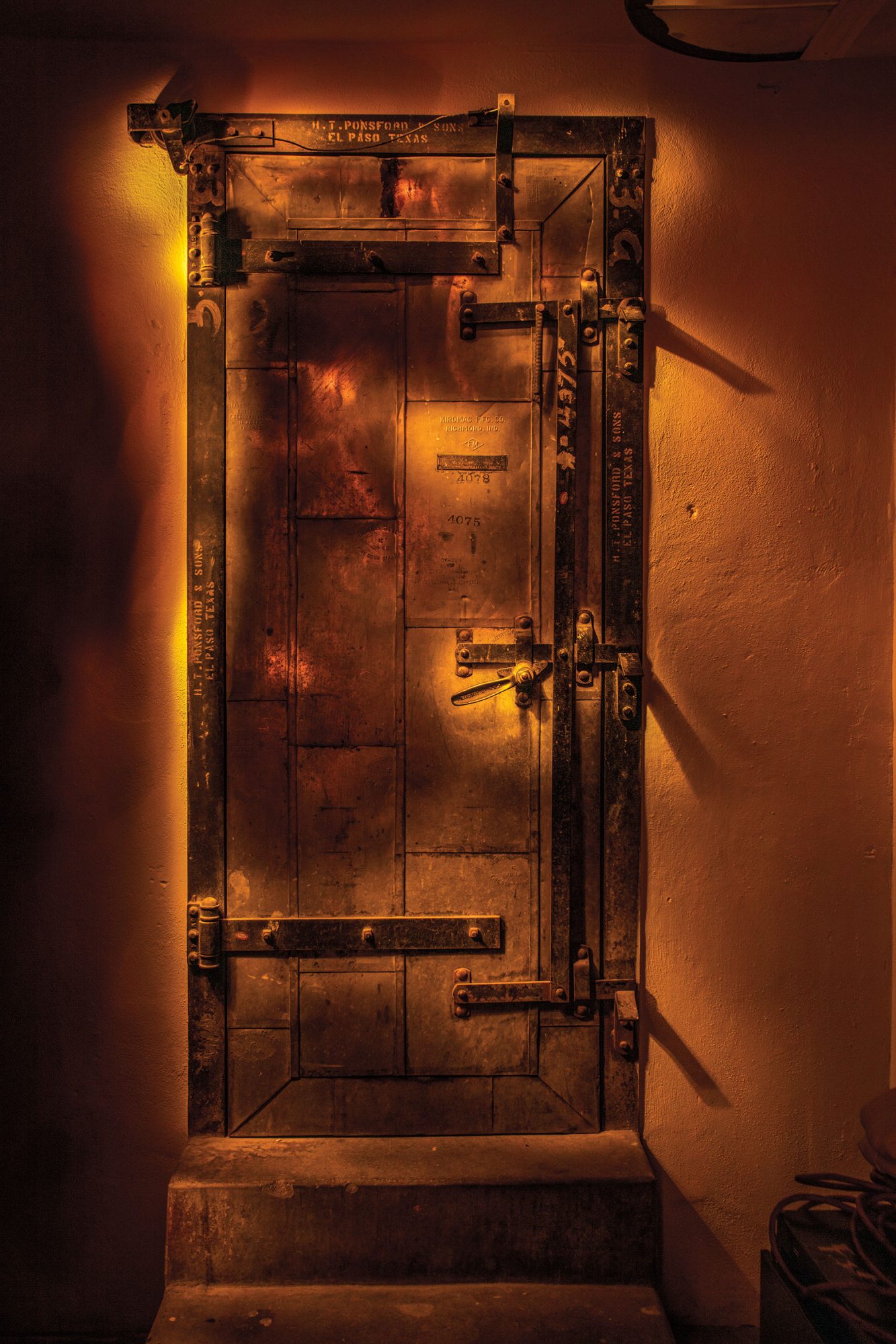 A spookily-lit door with numerous locks and chains in slight gold light