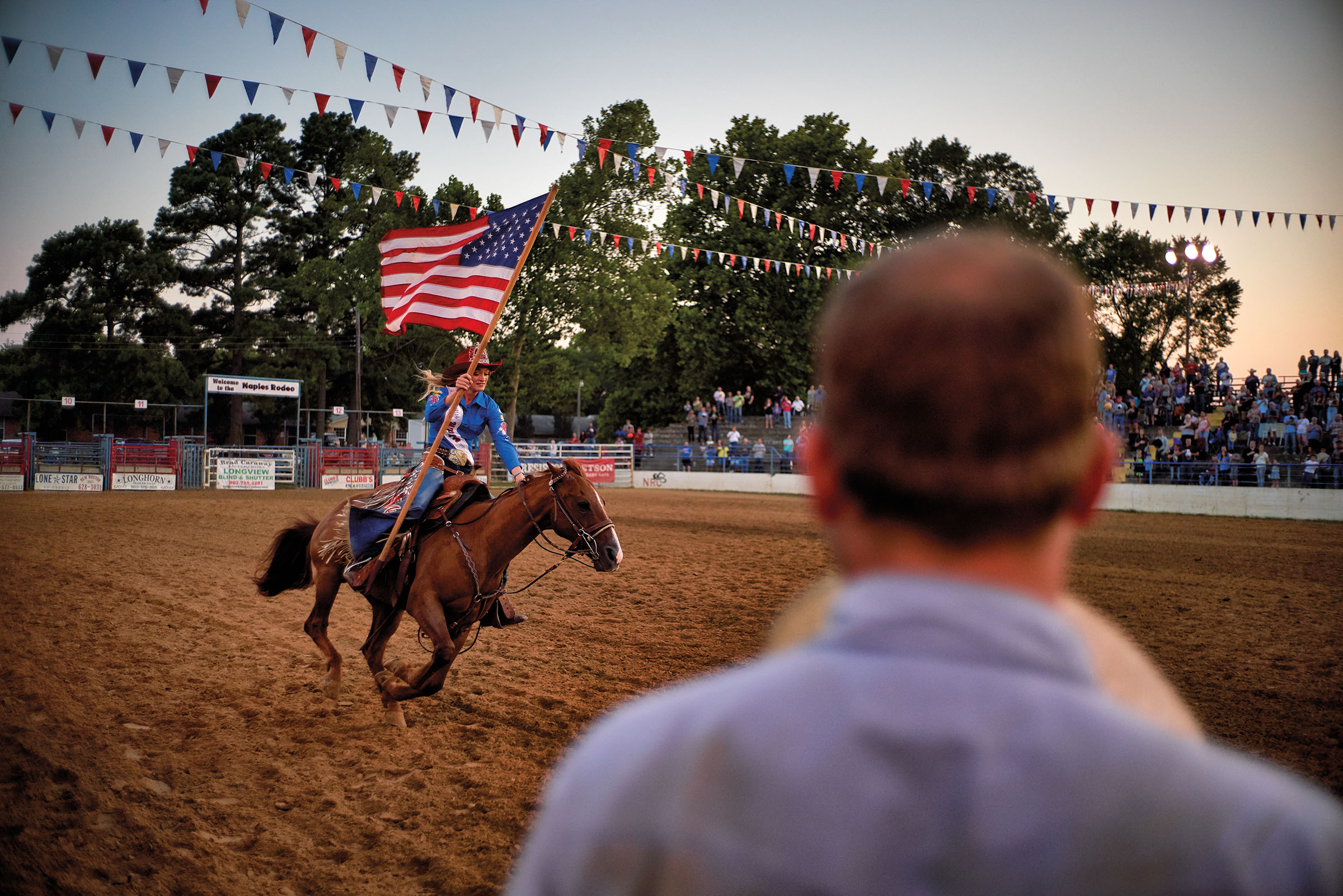 A woman rides a horse carrying the American flag during the Naples Watermelon Festival and Rodeo