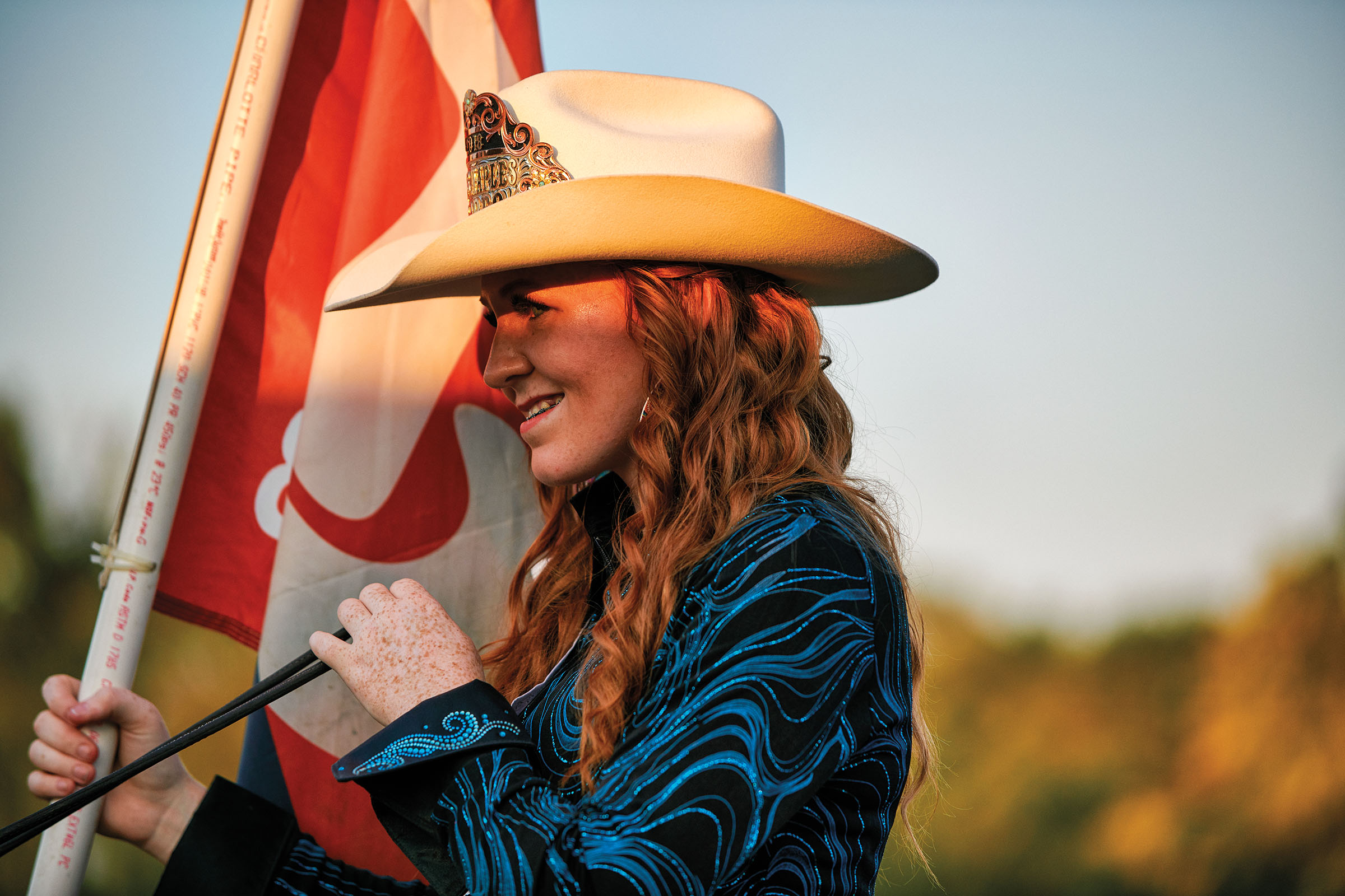 A young woman in a cowboy hat holds a flag during the Naples Watermelon Festival and Rodeo