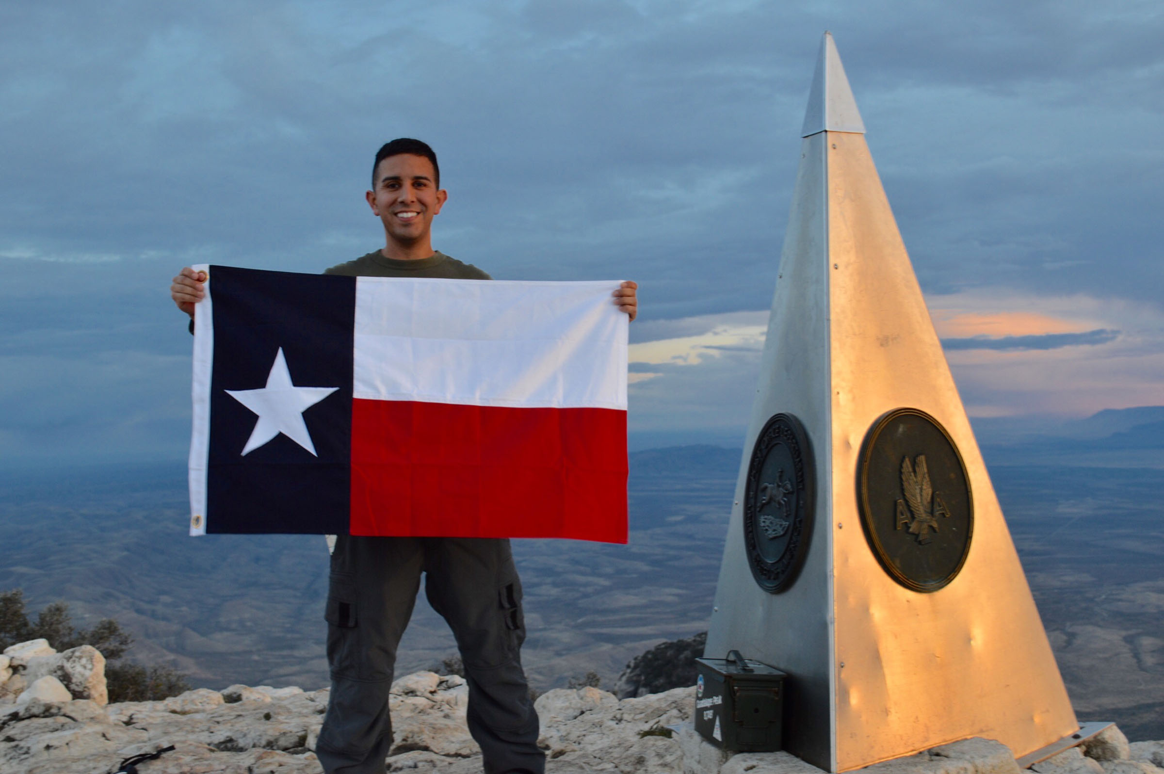 A man holds a Texas flag at the top of Guadalupe Peak in West Texas