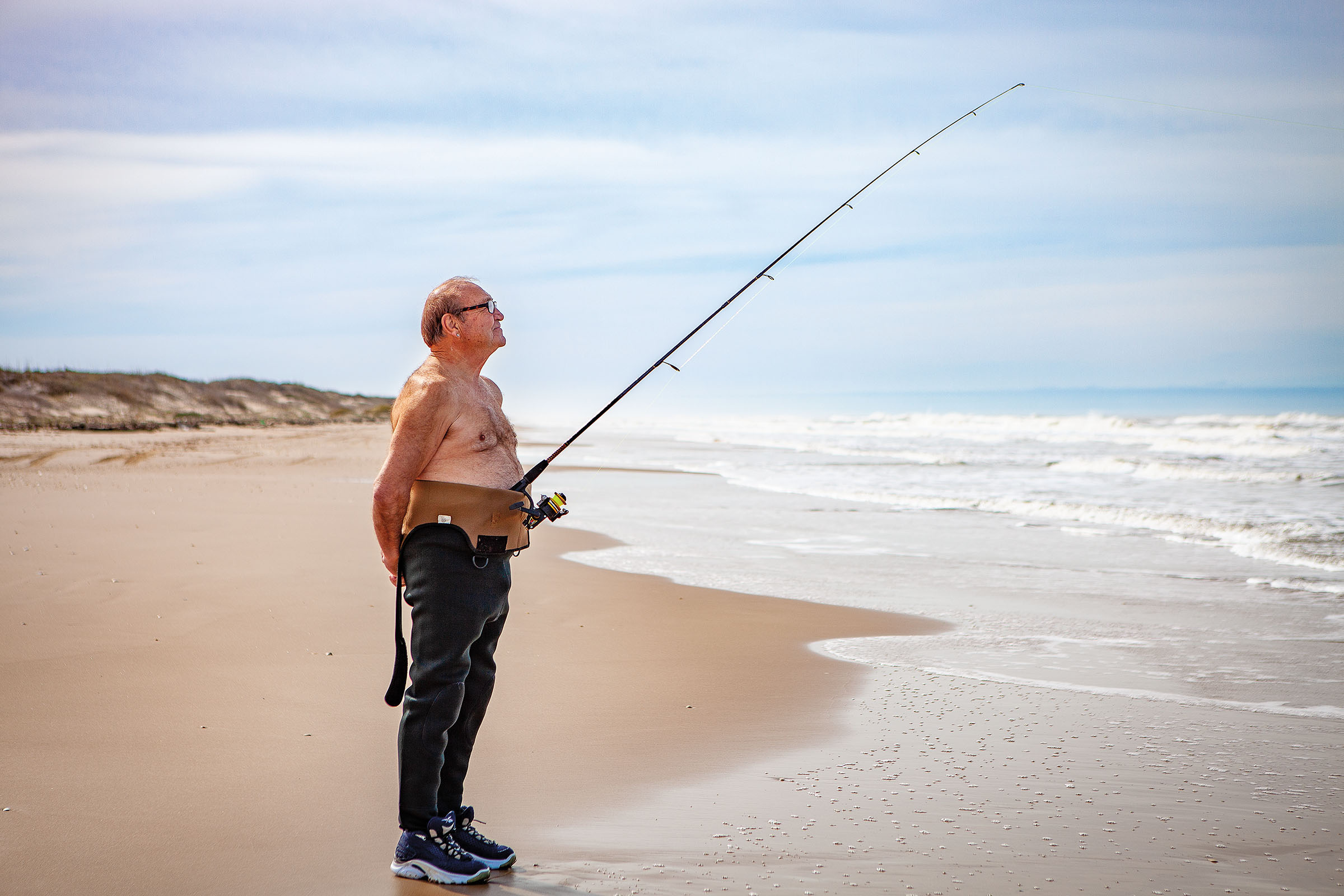 A fisherman finds a new way to hold his rod and reel while drying off on South Padre Island, Texas