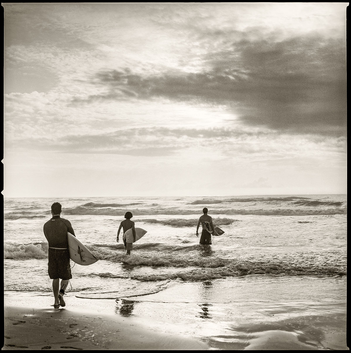 Surfers make their way into the waters of South Padre Island, Texas