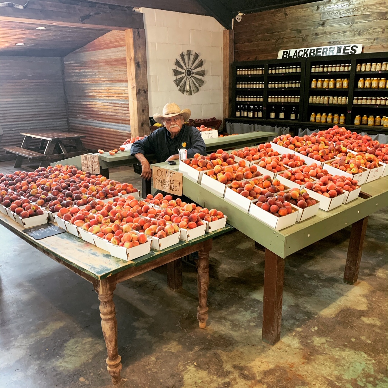 Travis Jenske of Jenske Orchards sits with boxes of fresh peaches