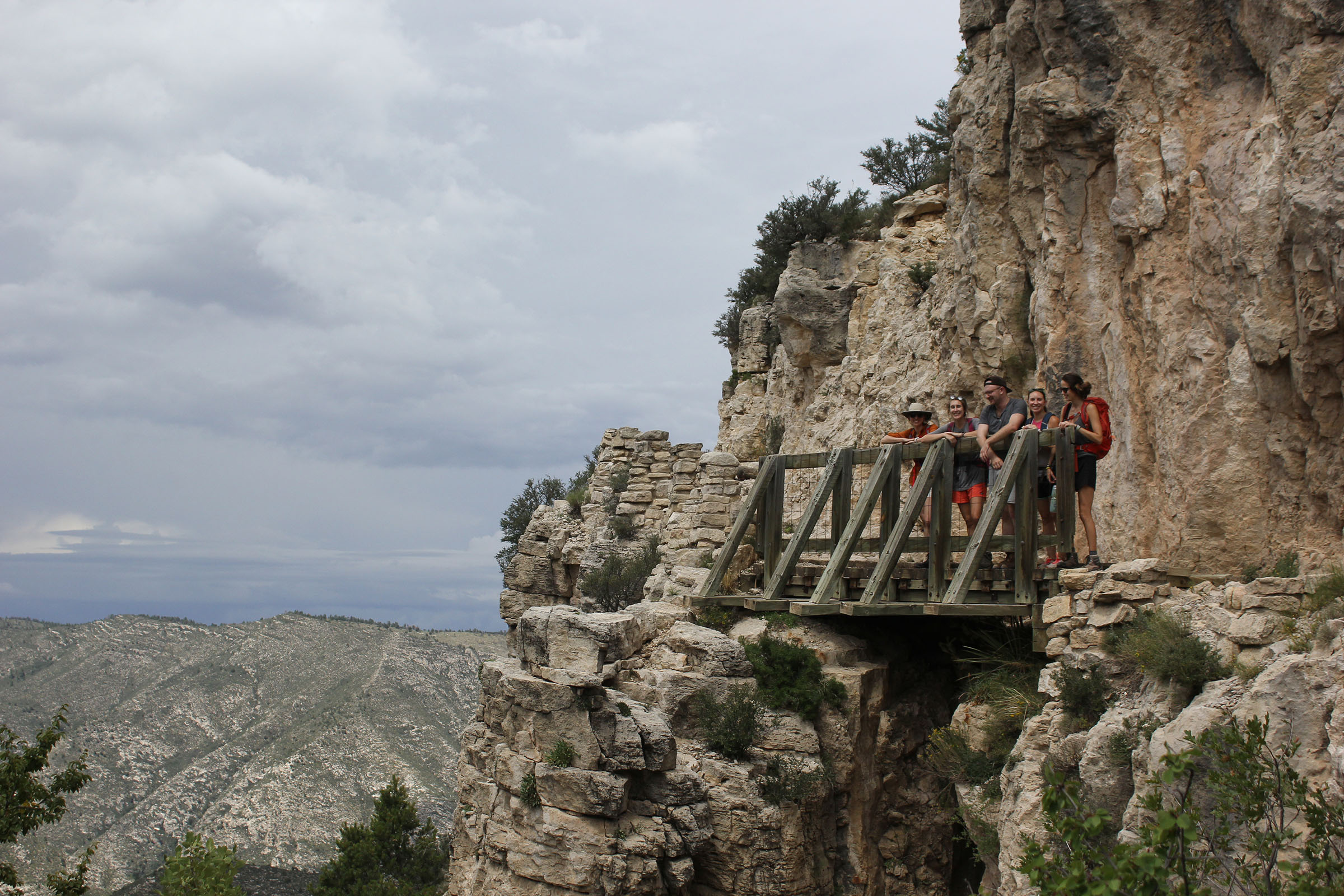 Hikers stand on a wooden bridge overlook on Guadalupe Peak Trail