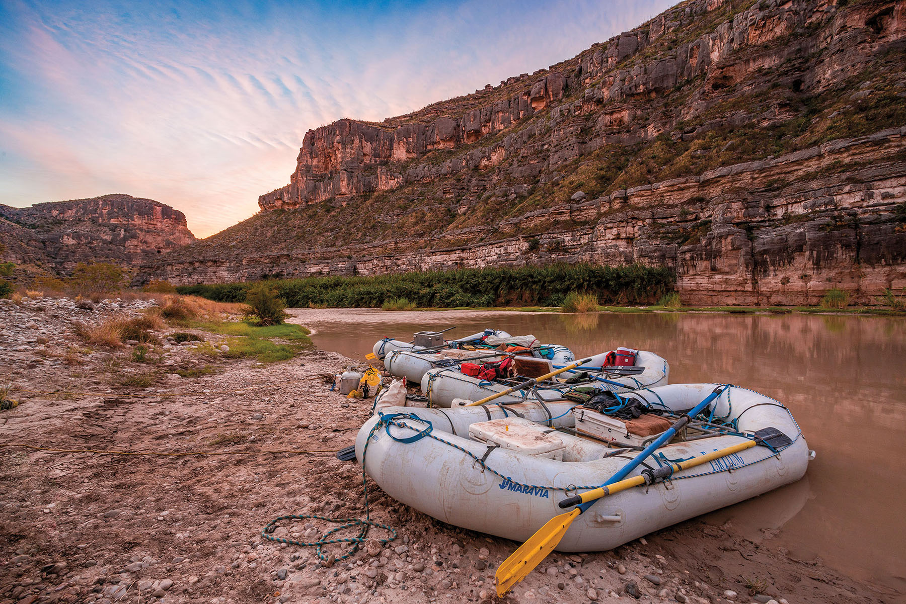 Four rafts parked on the banks of the Rio Grande at San Francisco Canyon