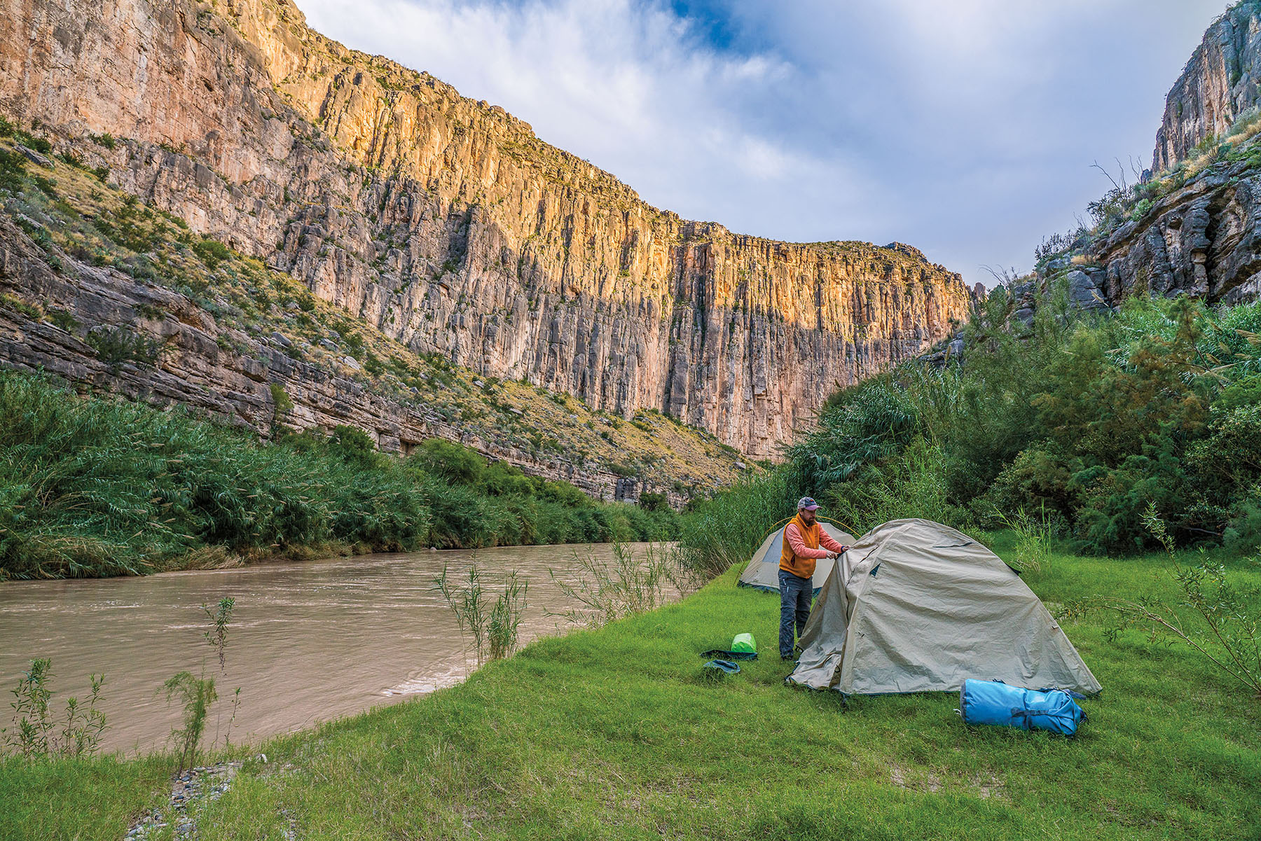 A man pitches a tent along the banks of the Rio Grande