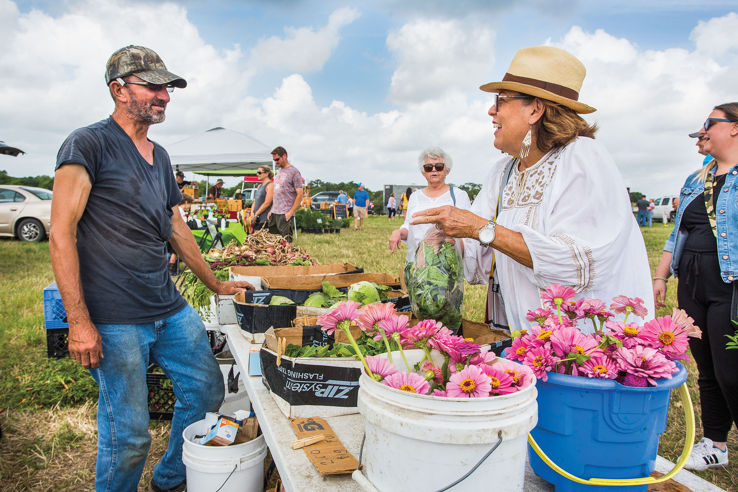 William Schilhab talks with Susan Romero as she picks out bag leafy greens from his stand at the La Grange Farmers Market at the Jersey Barnyard. 