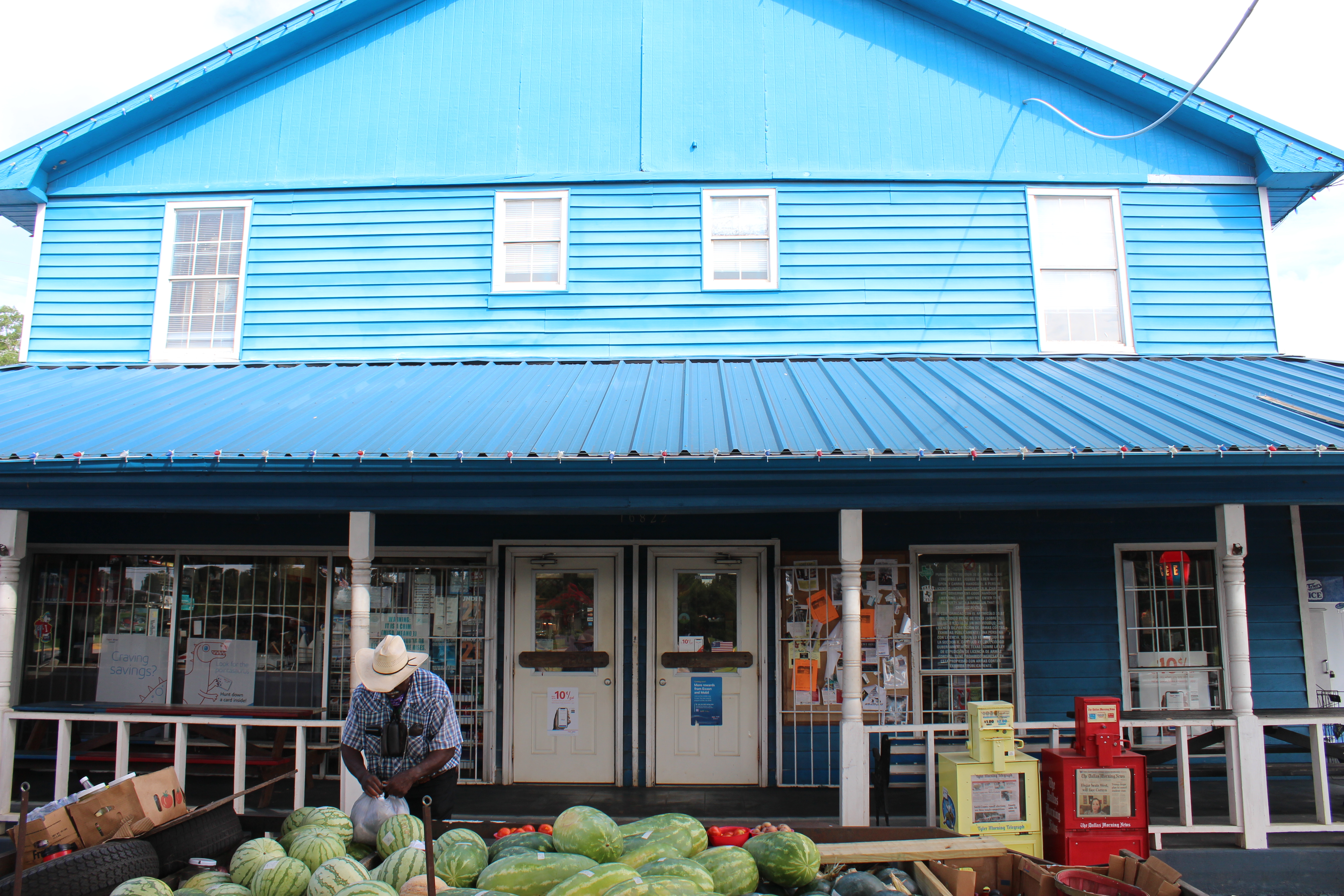 Herbert "Cowboy" Phillips stands outside of The Blue Store, alongside a large batch of watermelon.