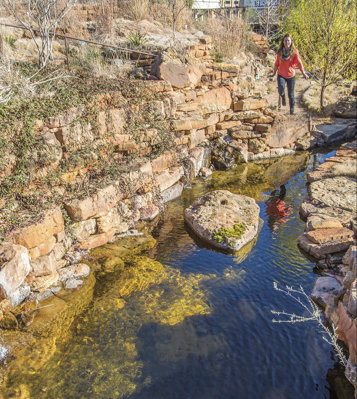 Woman walks near a creek.