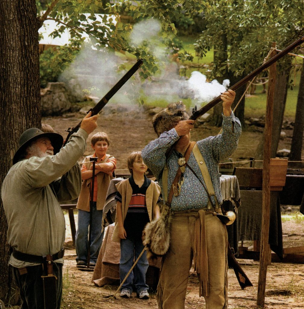 Two guys shooting old-time guns into the air.