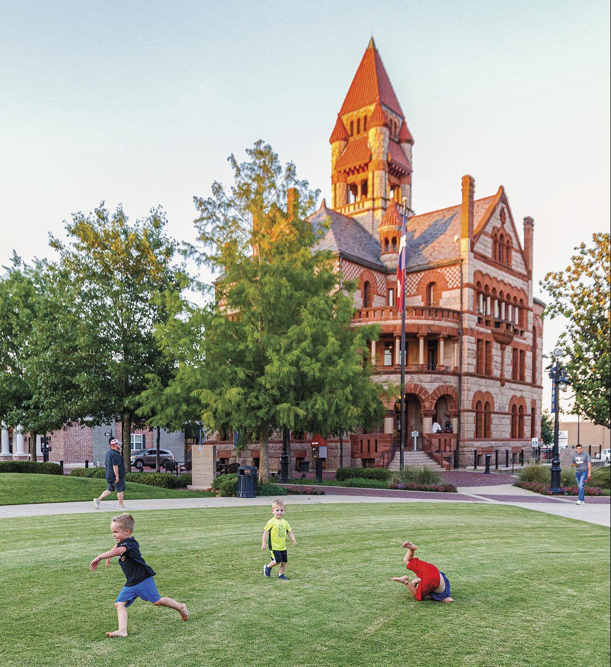 Three children run around in front of Hopkins County Courthouse