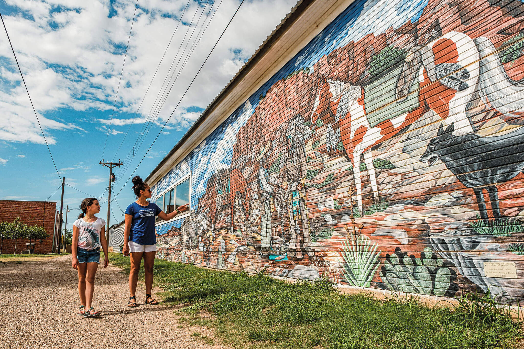 Two women look at a mural outside the The Milburn-Price Culture Museum. 