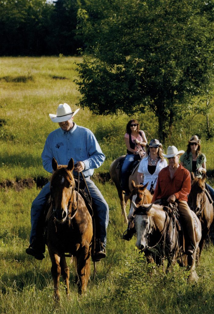 Lonesome Pine cowboy Craig Bauer and owner John Elick (in red) lead several guests on a horseback tour of the ranch. (Photo by Michael Amador)