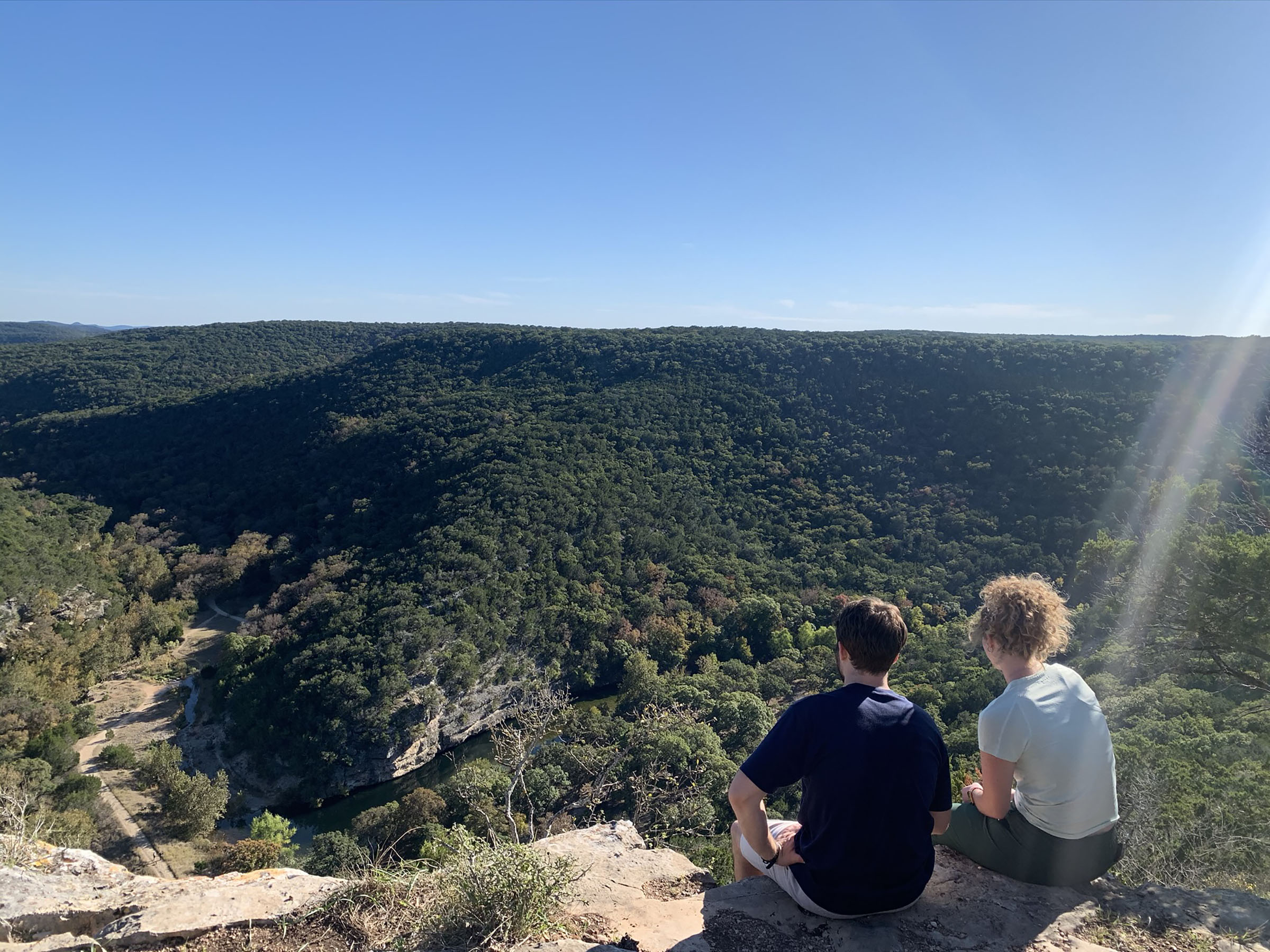 A man and woman sit on rocks atop a bluff in Lost Maples State Natural Area in the Texas hill country