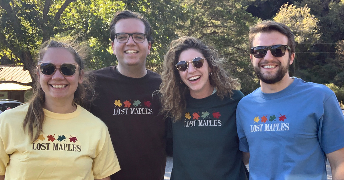 A group of people pose in T-shirts and crewnecks reading "Lost Maples"