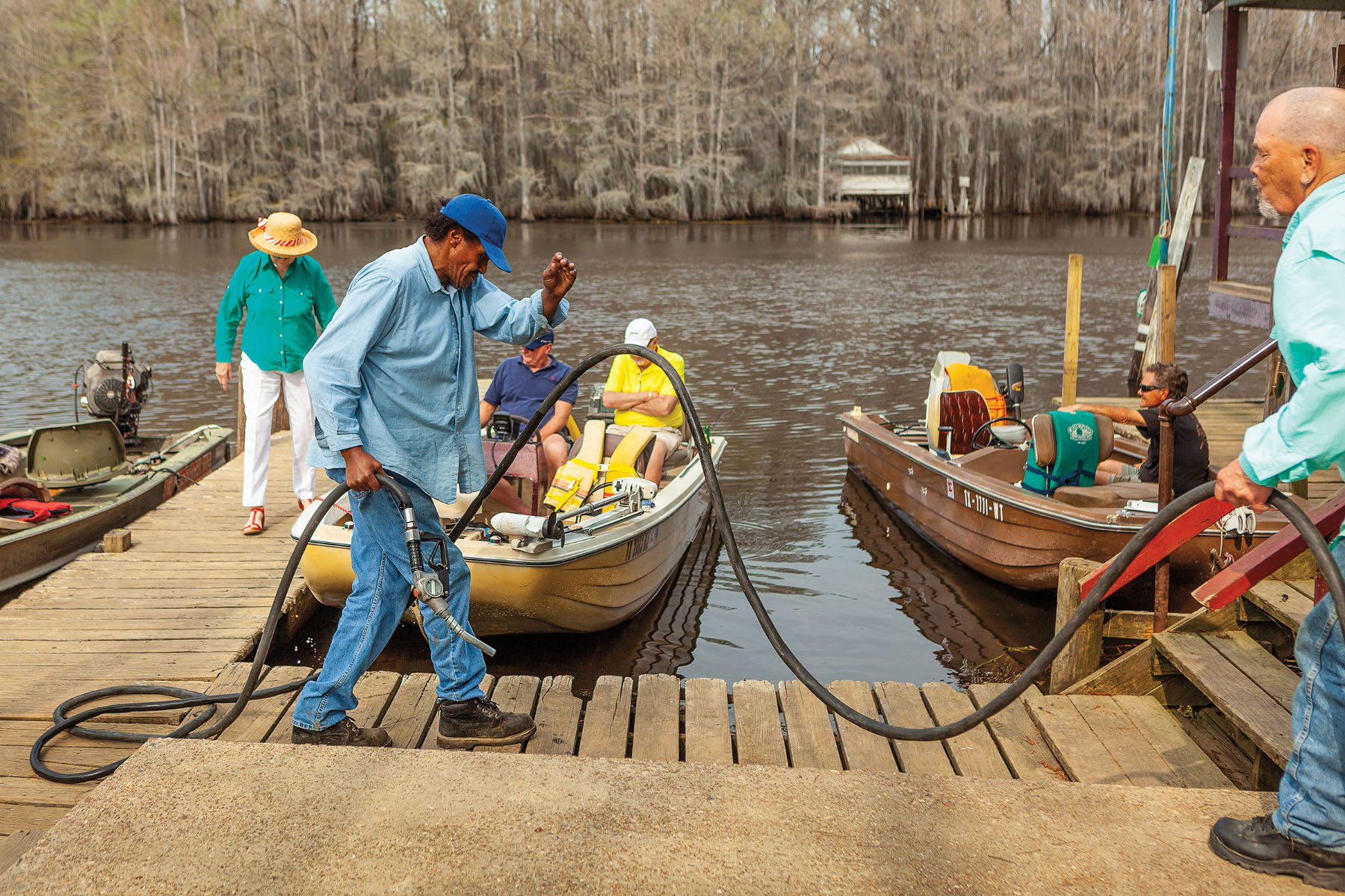 At Johnson’s Ranch Marina on Caddo Lake, the men in the foreground finish pumping gas into a boat while another boat returns from a successful fishing excursion.