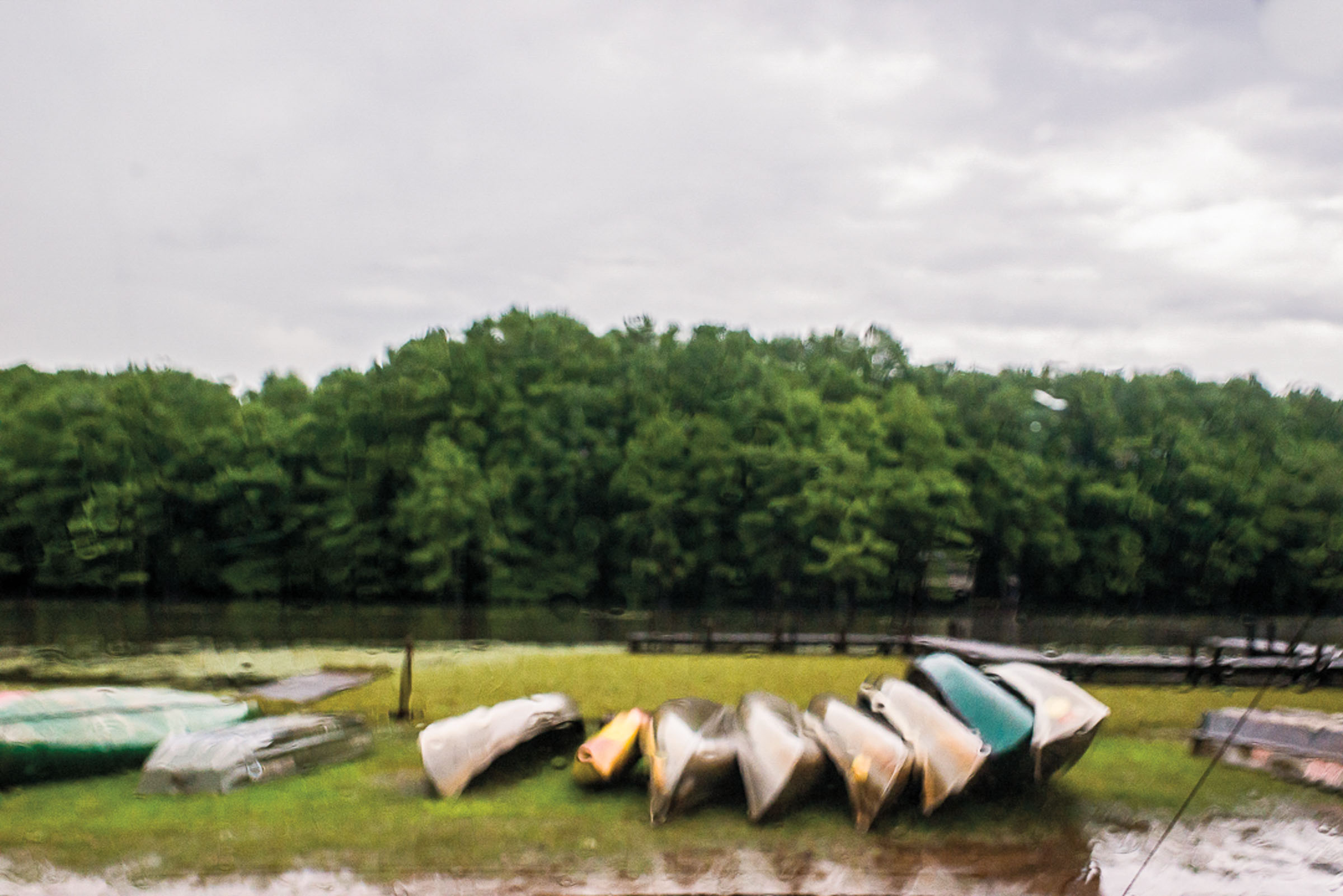 On a rainy day, canoes are lined up waiting for someone to use them near Caddo Lake and Uncertain, Texas