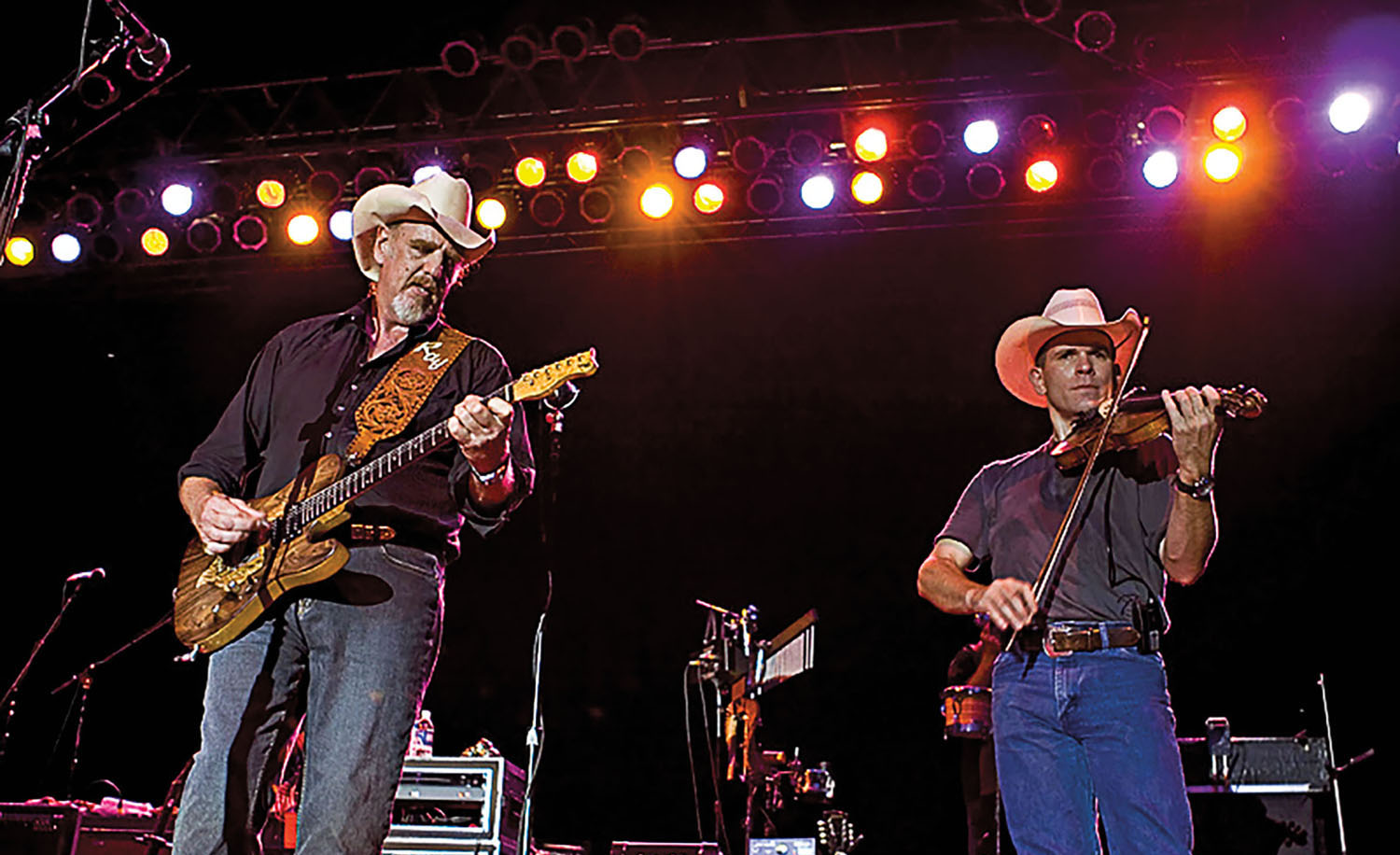 Ray Benson and Jason Roberts perform under stage lights