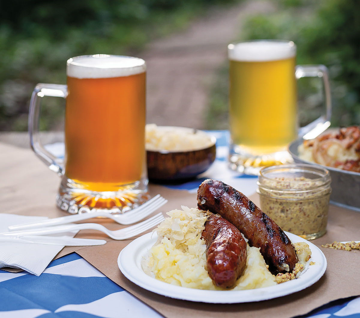 Two sausages on a pile of sauerkraut with mustard and beer