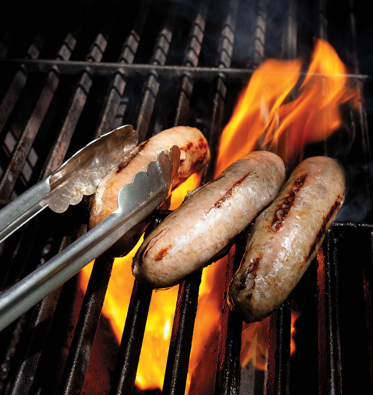 Sausages cook on a flaming grill