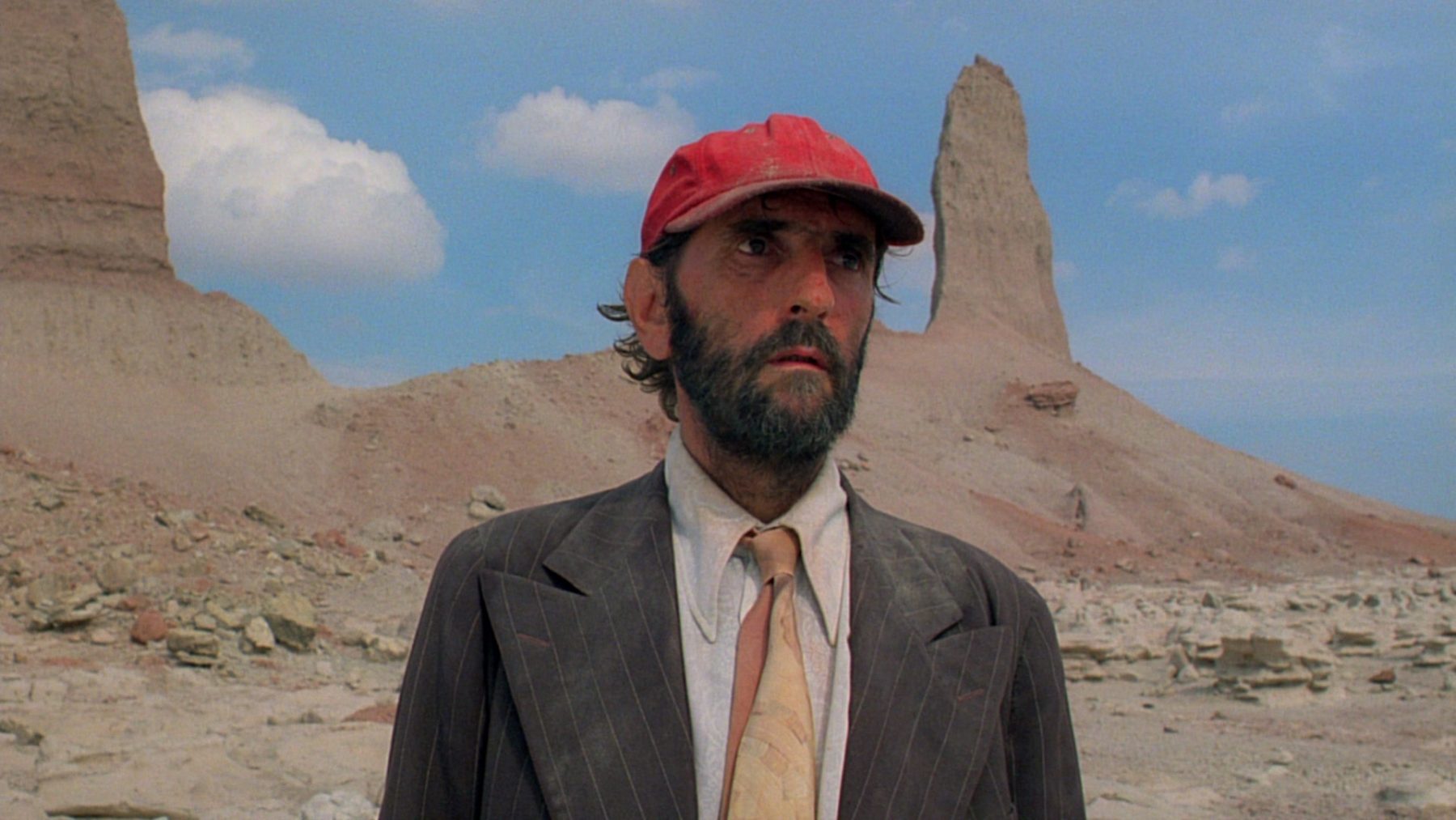 Photo of bearded man with red hat in the desert