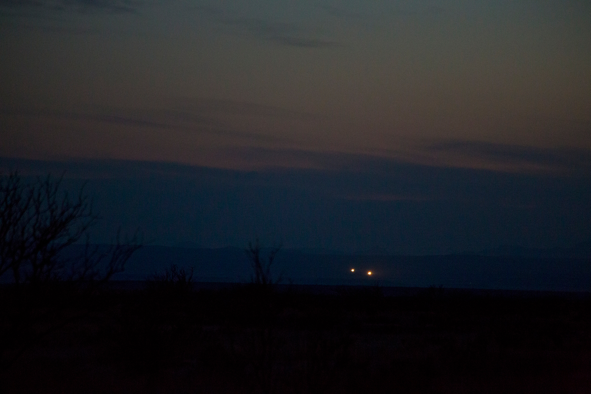 Two orbs glow in a dark sunset outside of Marfa