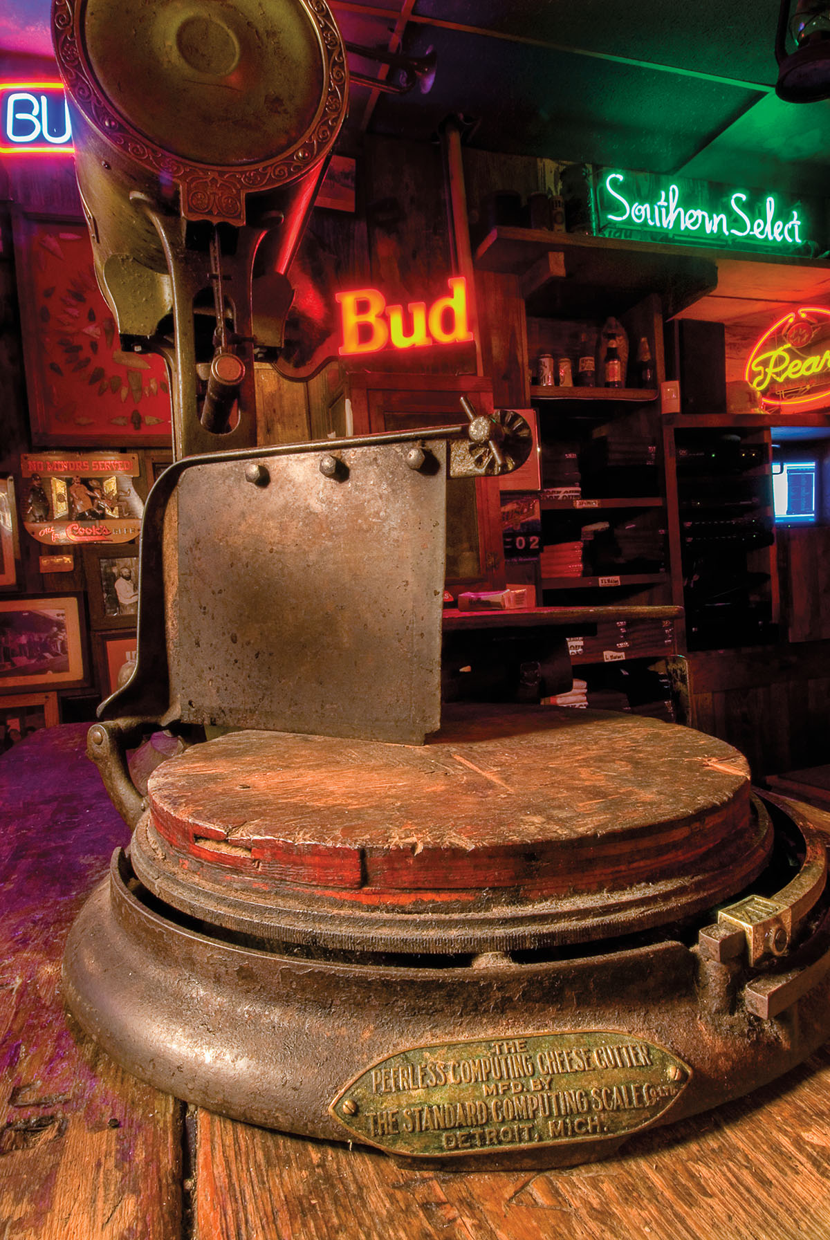A vintage cheese cutter in front of neon signs at the Dixie Chicken bar