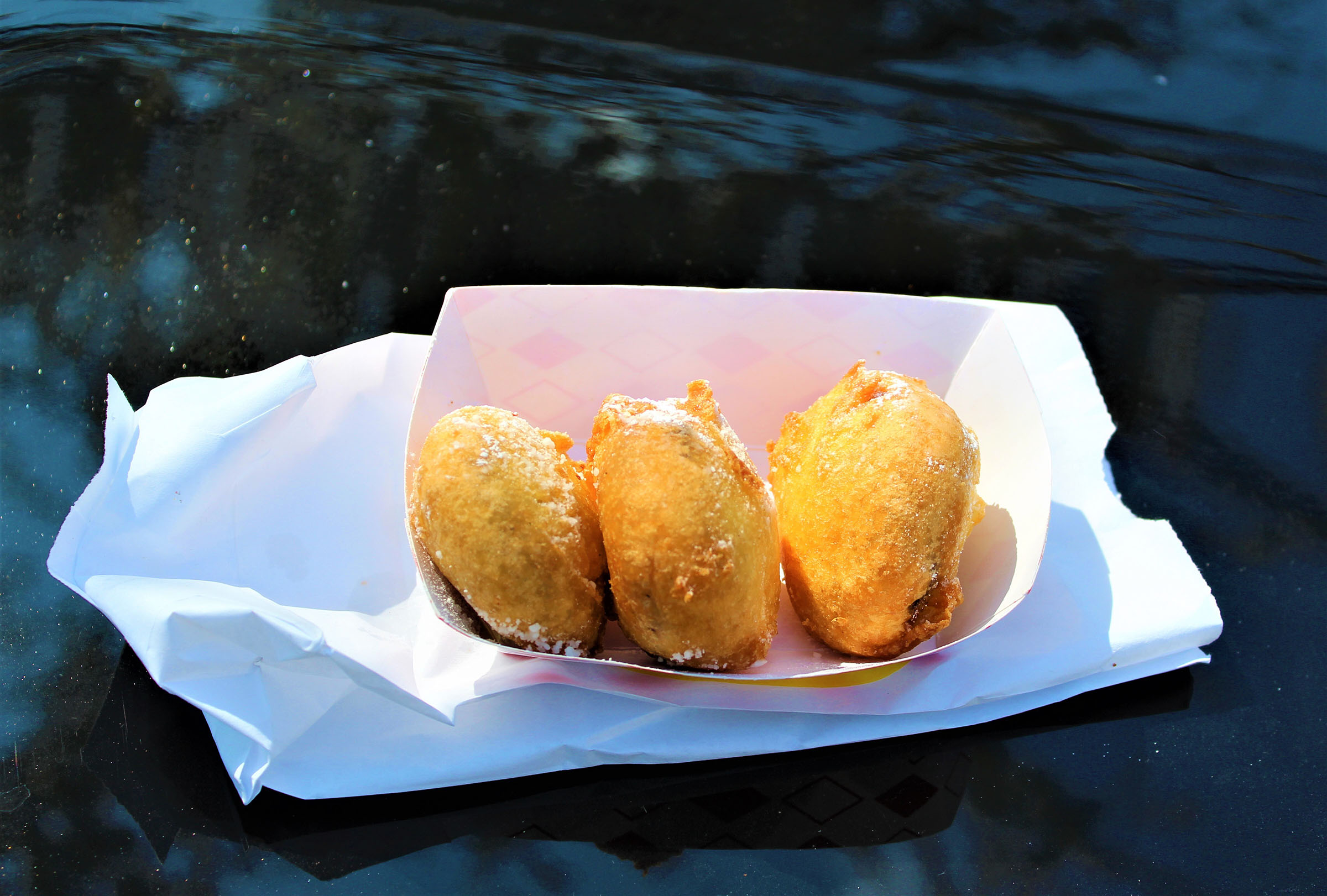 A small paper boat with three fried oreos