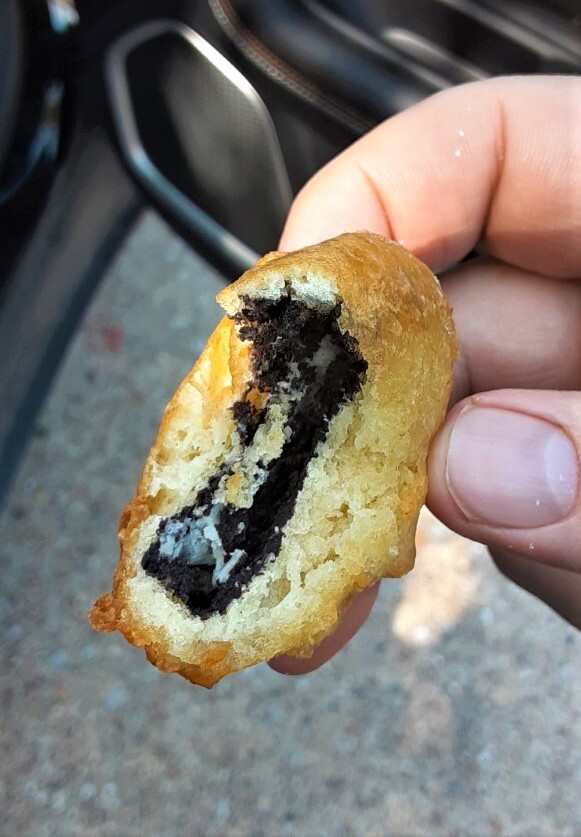 A close-up photo showing a bite taken out of a deep-fried oreo