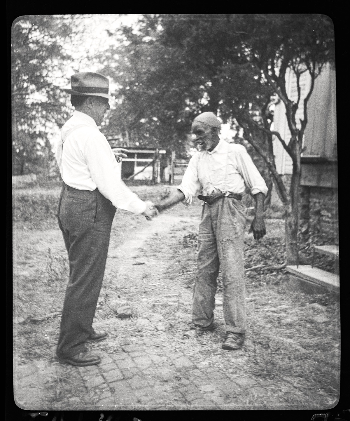 Two men shake hands along a path