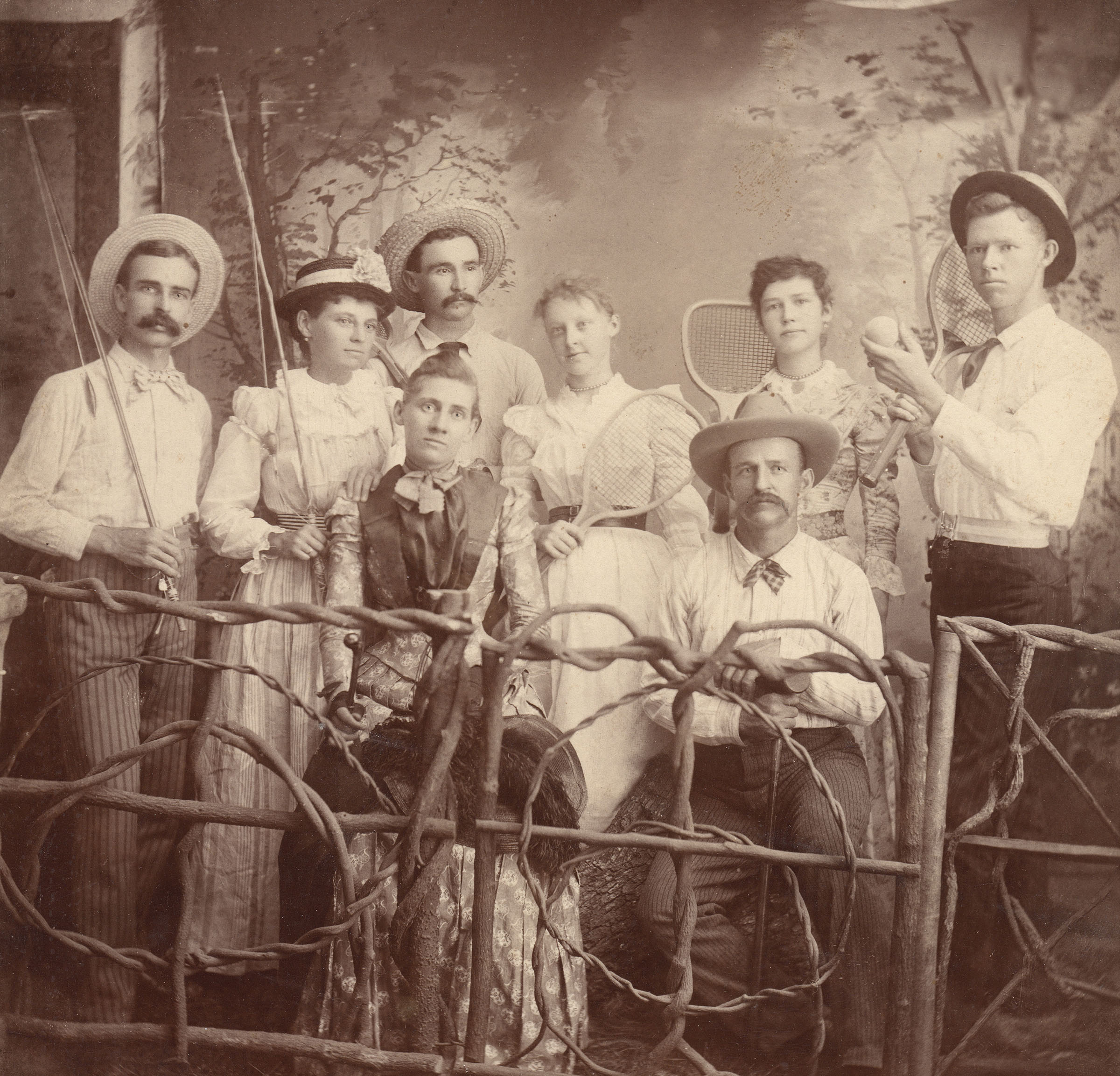A group of people use props and funny faces in a vintage photo, including fishing poles and tennis rackets