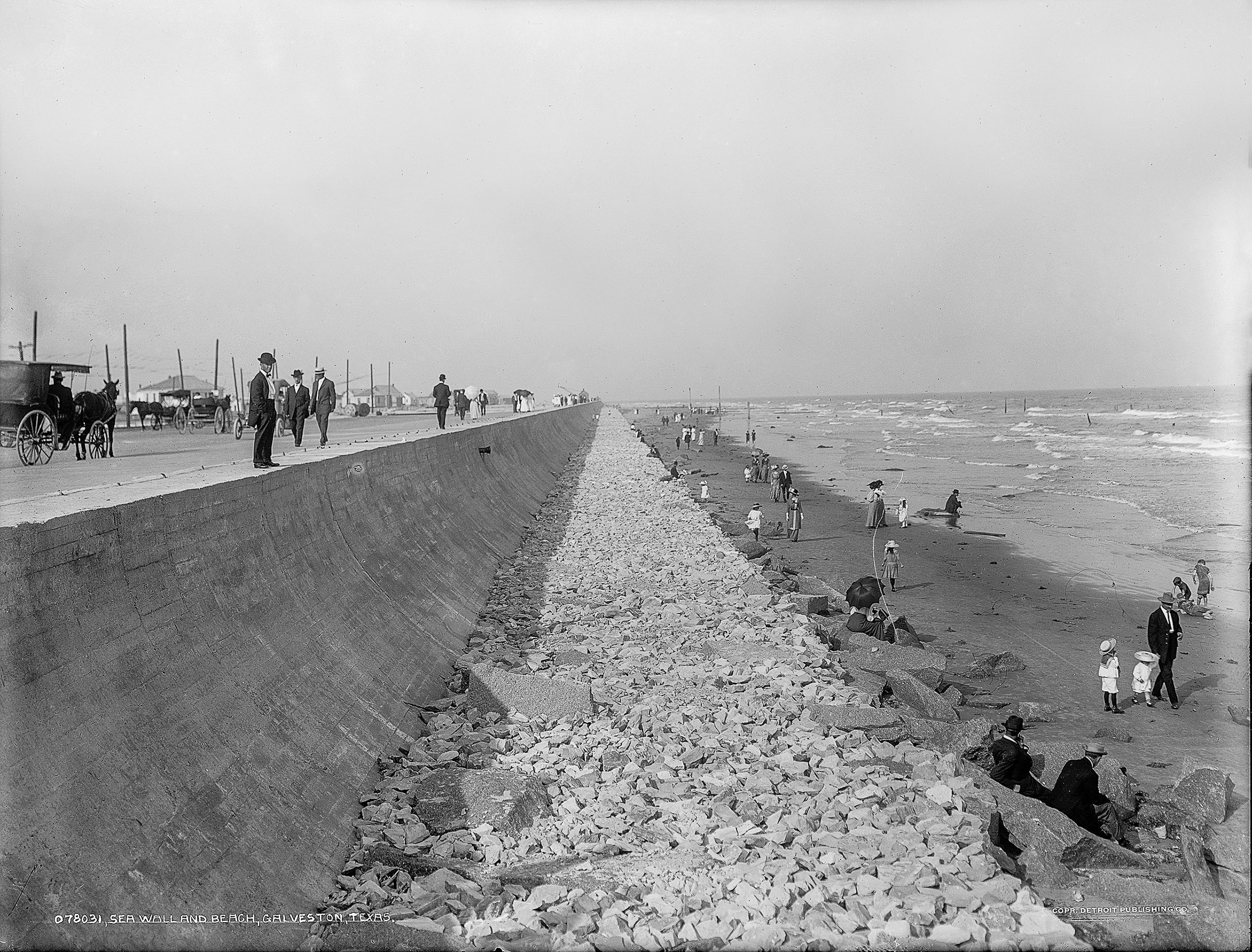 People walk along the road and shore on the Galveston Seawall after the hurricane